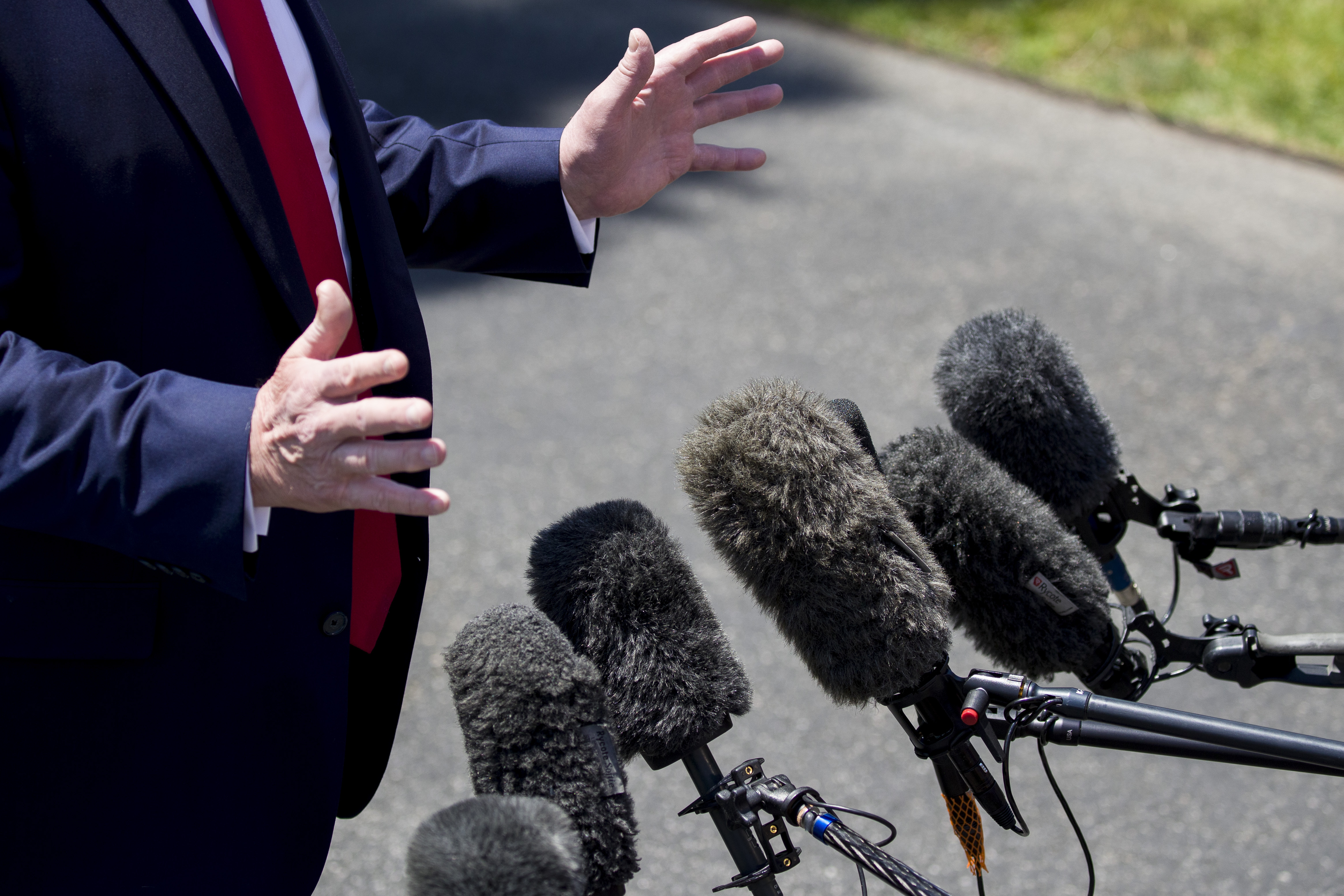 FILE - Microphones are extended as President Donald Trump speaks with reporters on the South Lawn of the White House, in Washington, June 26, 2019. (AP Photo/Alex Brandon, File)
