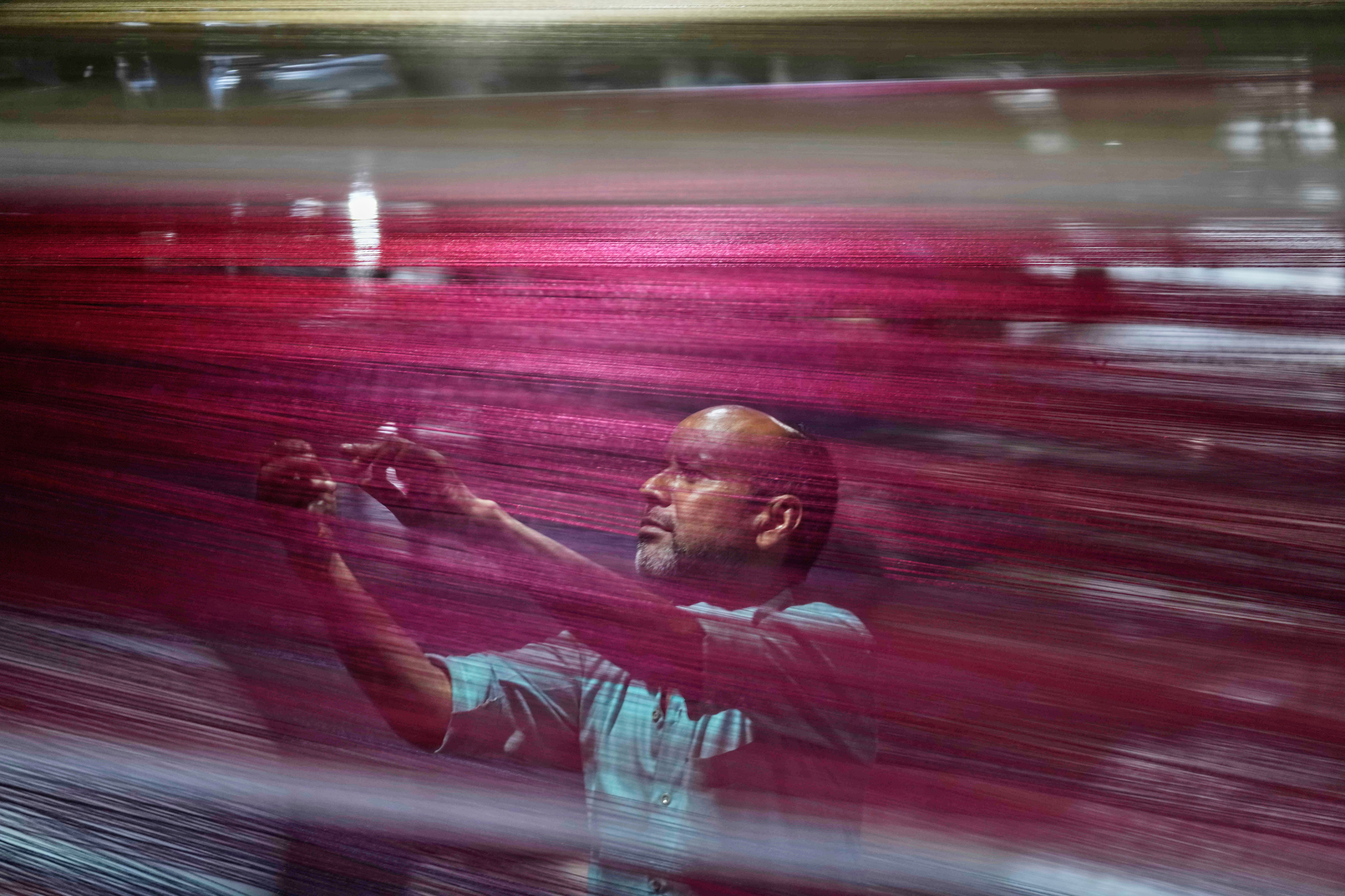 An Indian worker checks thread reels on a carpet weaving machine at a factory on the outskirts of Jammu, India
