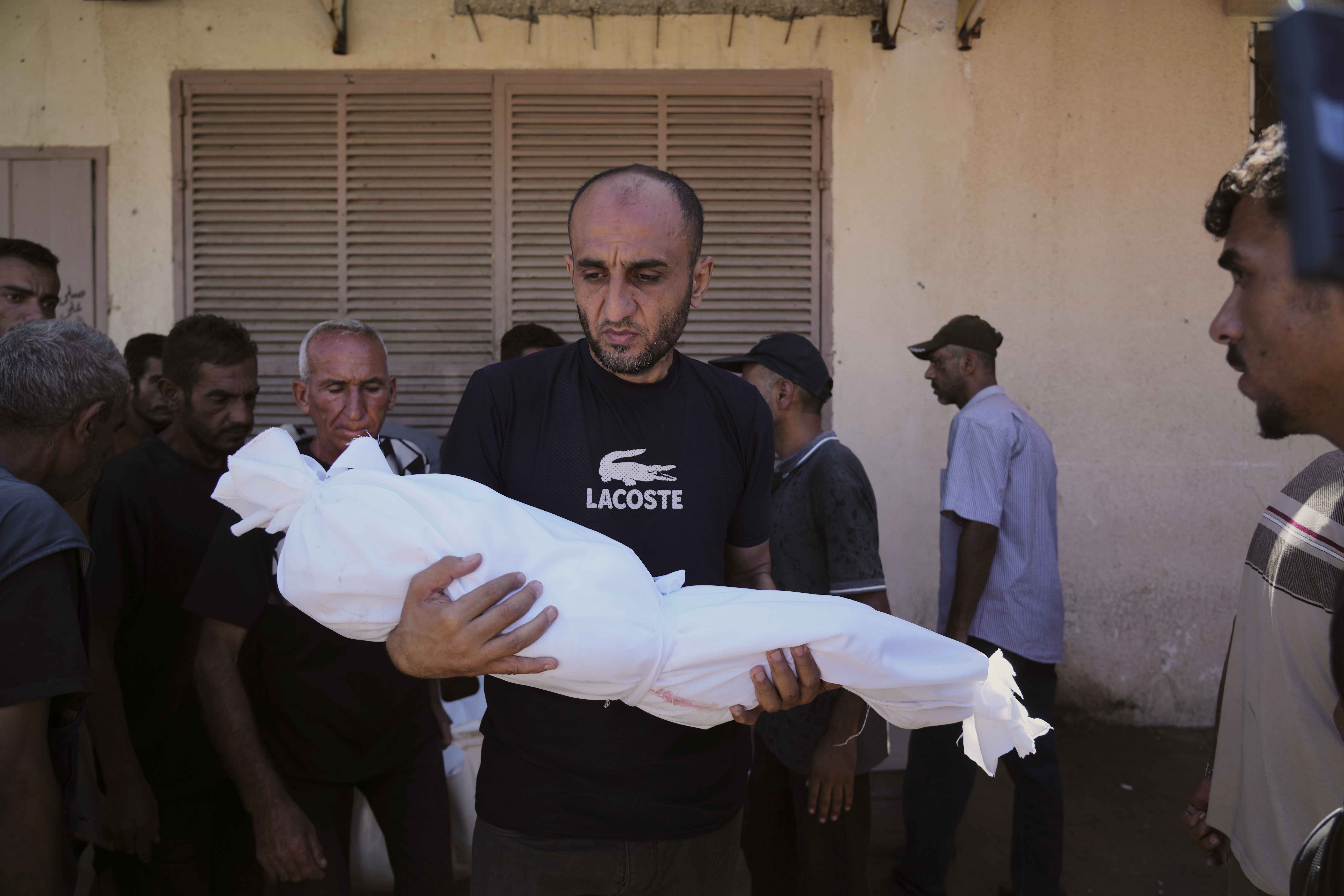 A man carries the body of 3-year-old Palestinian child Nour Abu Ouda, killed in an Israeli airstrike on the Gaza Strip, at Al-Aqsa Hospital in Deir al-Balah, Sunday, Sept. 14, 2025. (AP Photo/Abdel Kareem Hana)