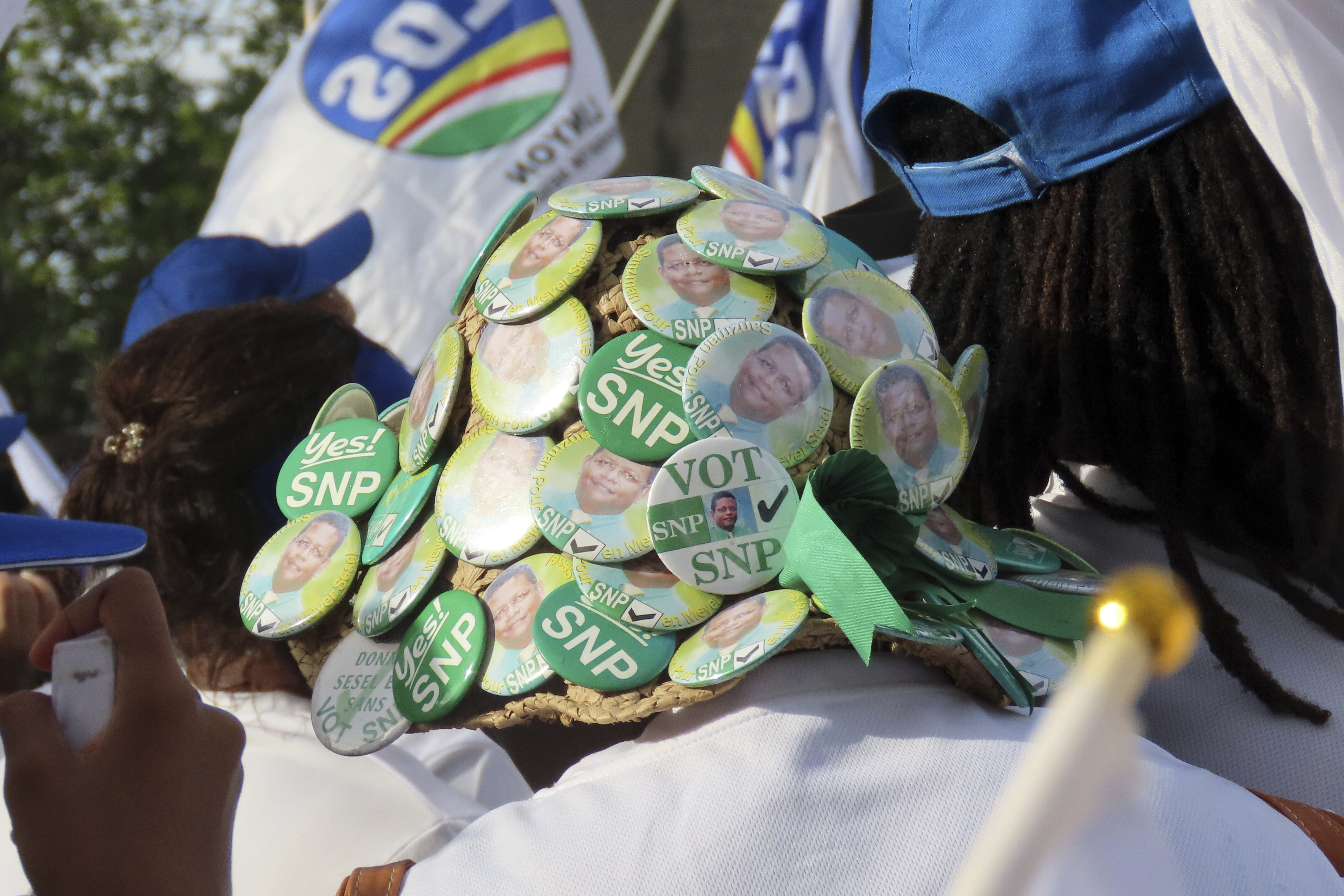 A supporter wears a hat pinned with the symbols of the Seychelles National Party, a former opposition political party, during a campaign rally at Freedom Square in Victoria, Seychelles on September 21, 2025.