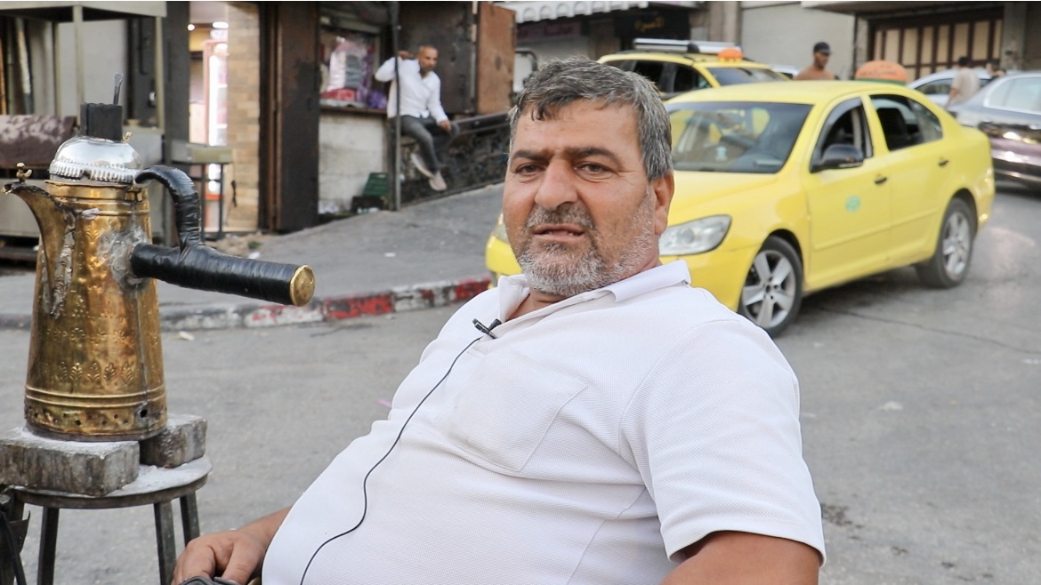 Man sits by his coffee pot in the market