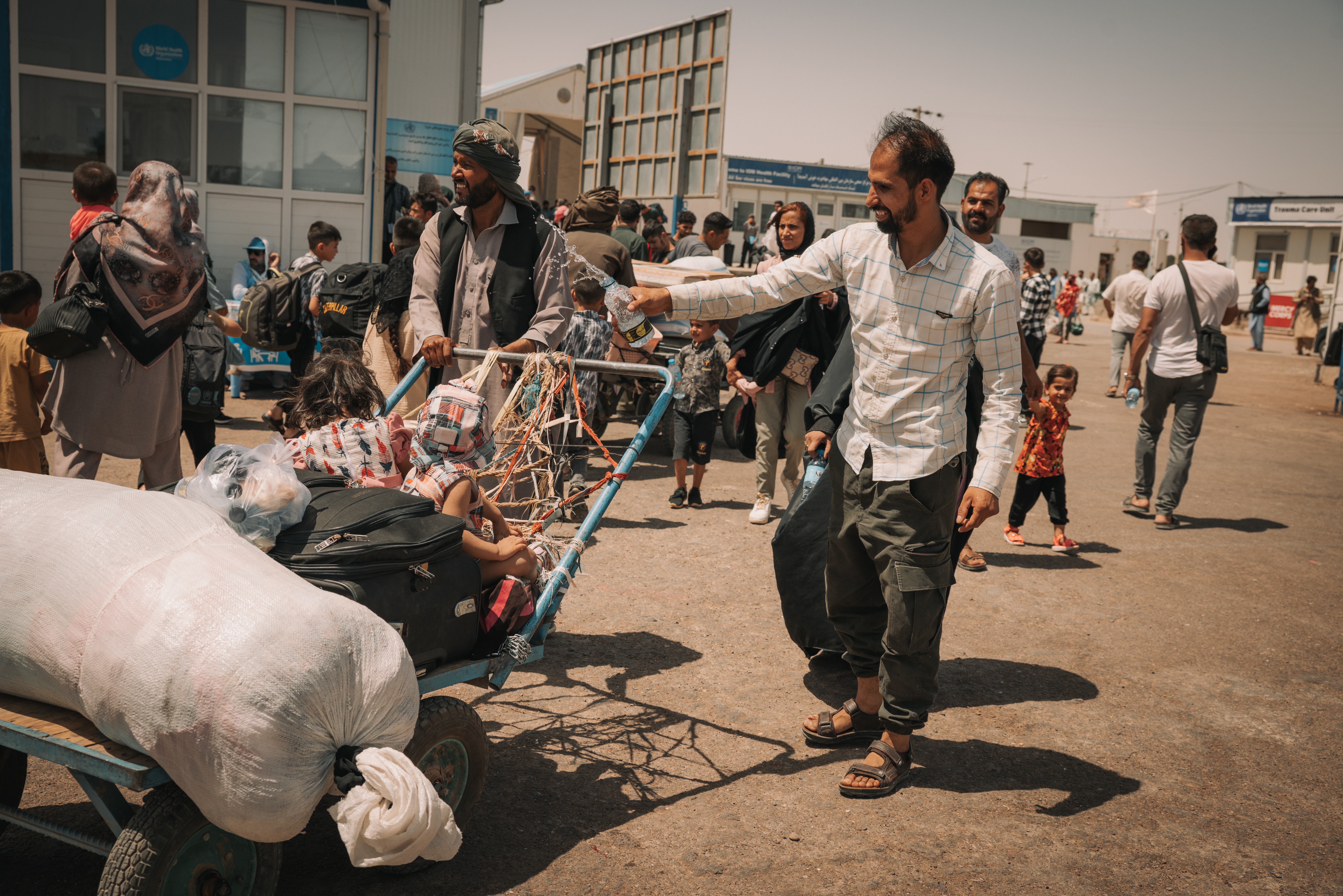 At Islam Qala, a father cools his children with water in the 40°C heat on their way to the IOM reception centre.