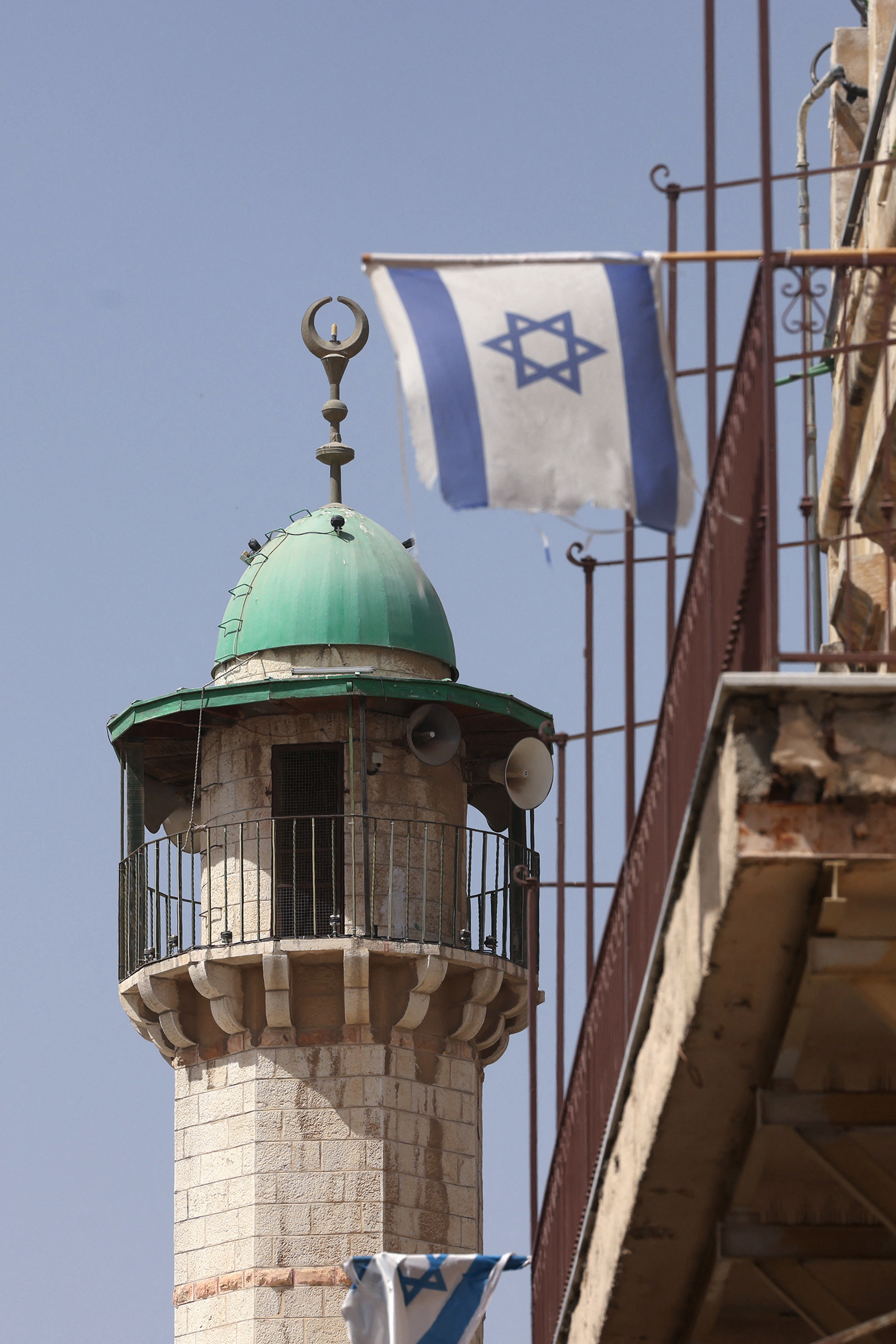 An Israeli flag flutters on a balcony near a mosque in the Old City of Jerusalem on September 21, 2025. (Photo by HAZEM BADER / AFP)
