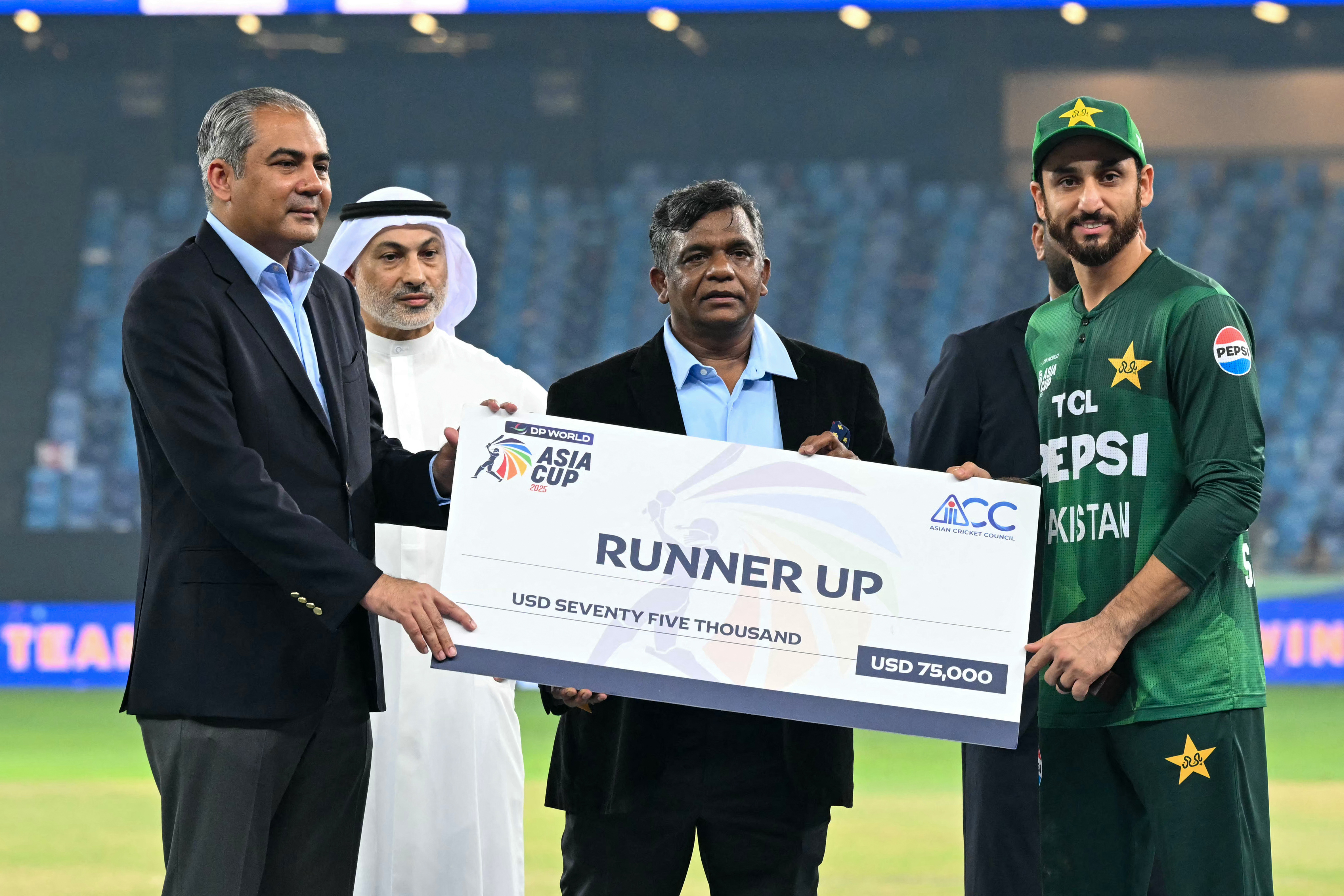 Pakistan's captain Salman Agha (R) receives the runner up cheque from Asian Cricket Council (ACC) and Pakistan Cricket Board (PCB) chairman Mohsin Naqvi during the presentation ceremony at the end of the Asia Cup 2025 Twenty20 international cricket final match between India and Pakistan at the Dubai International Stadium in Dubai on September 28, 2025.