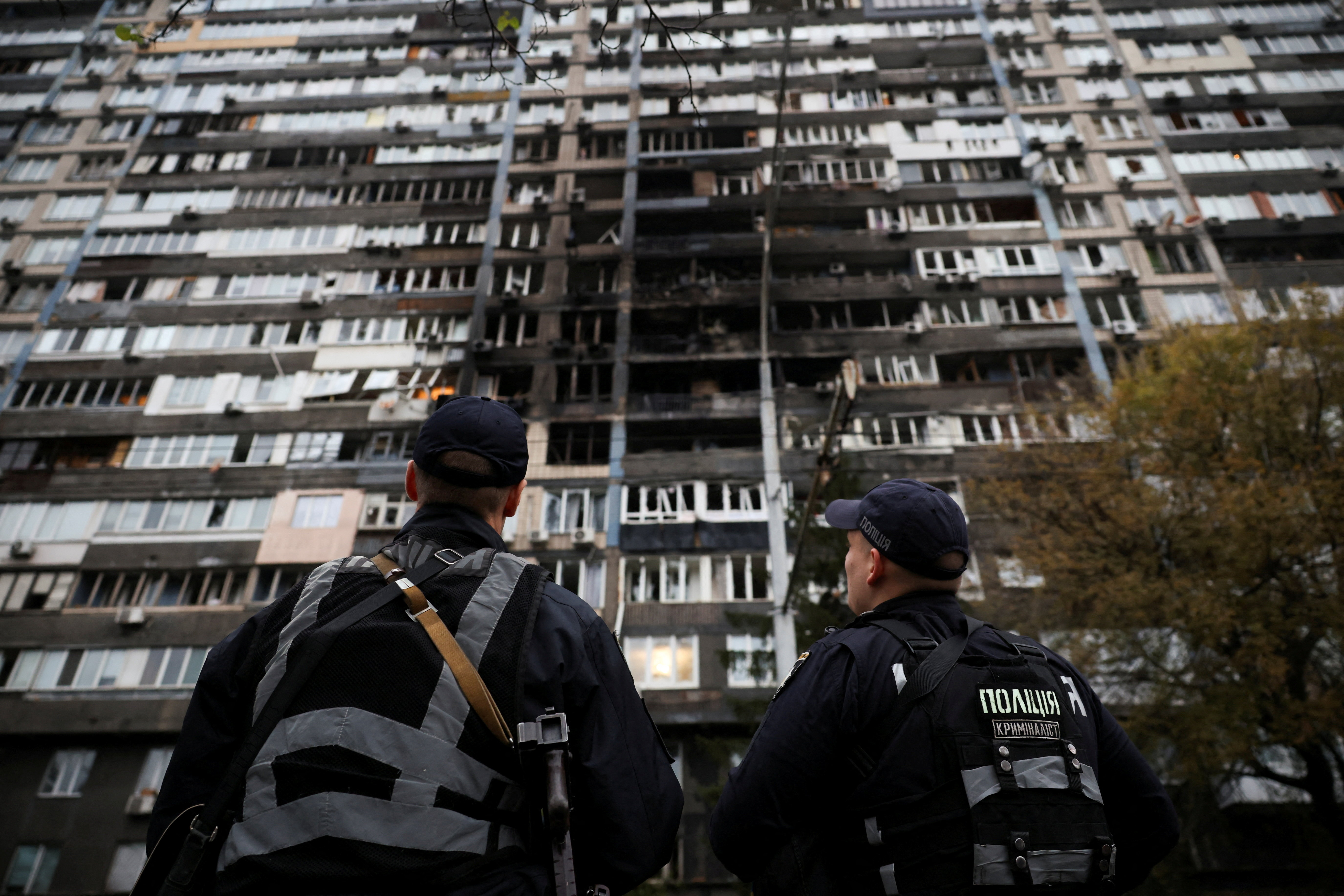 Police investigators look at an apartment building that was damaged during a Russian drone and missile strike in Kyiv on October 10, 2025.