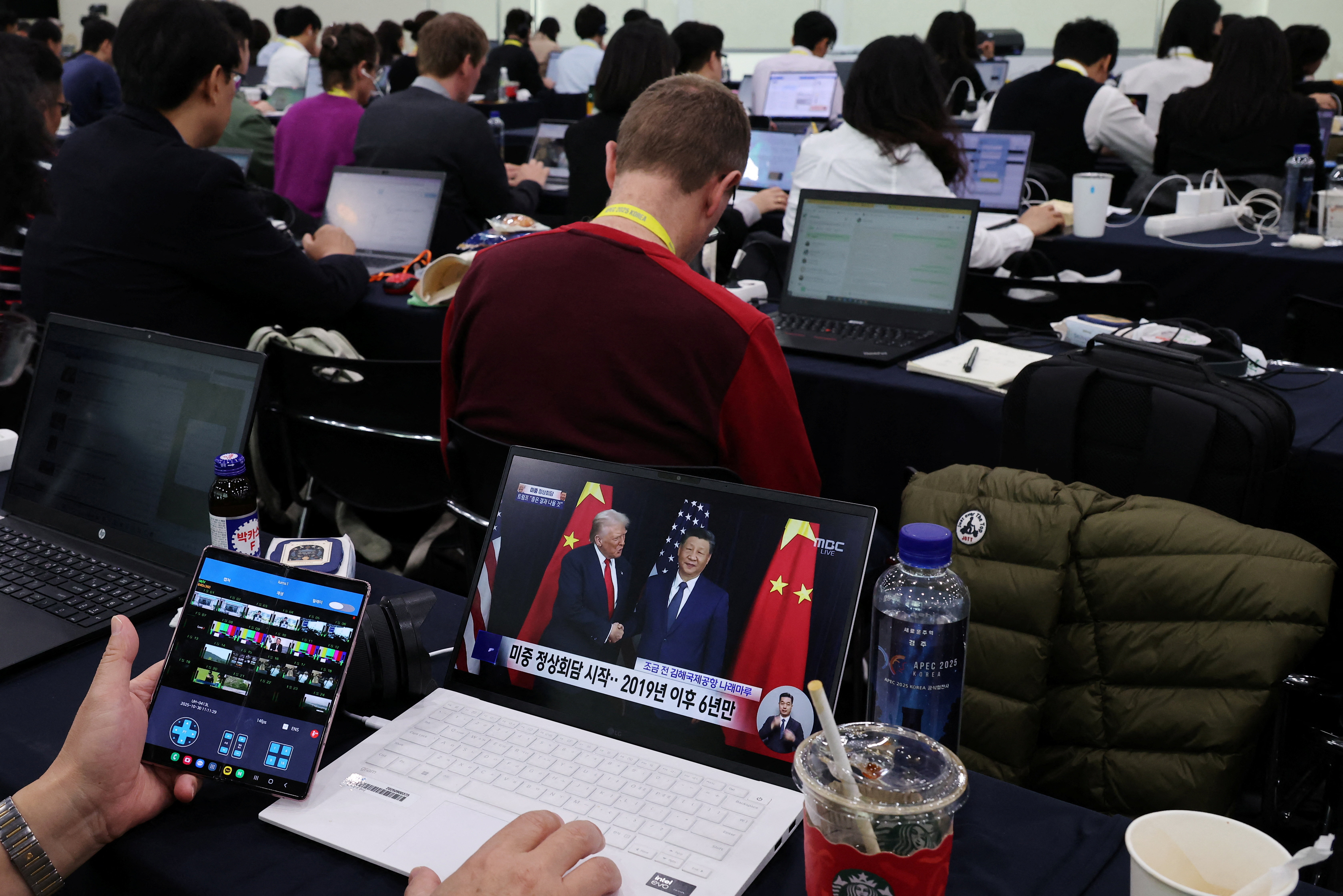 A member of the media watches a news broadcast of the meeting between U.S. President Donald Trump and Chinese President Xi Jinping
