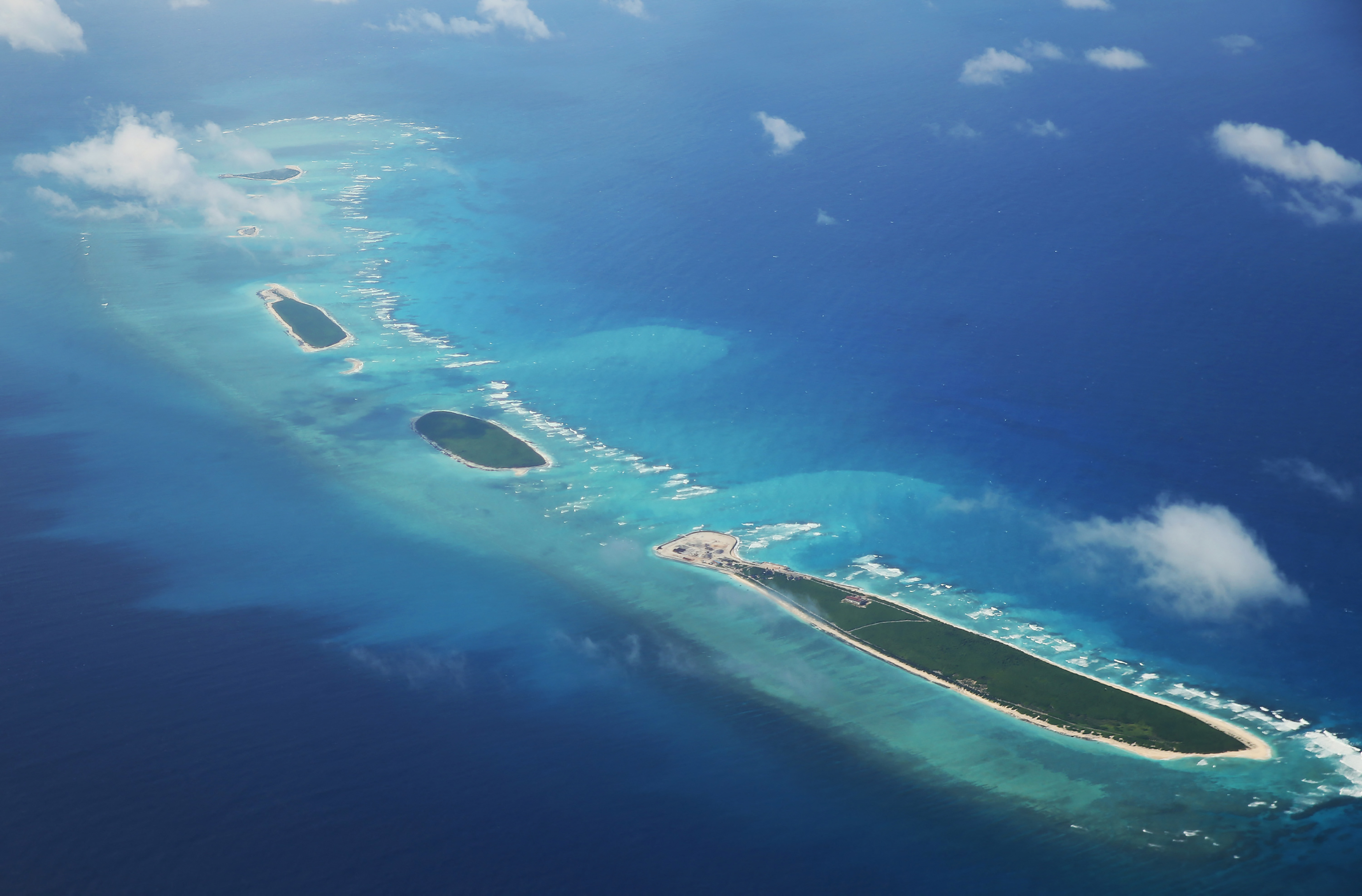 an aerial view of some islands covered in trees and sand in a blue ocean