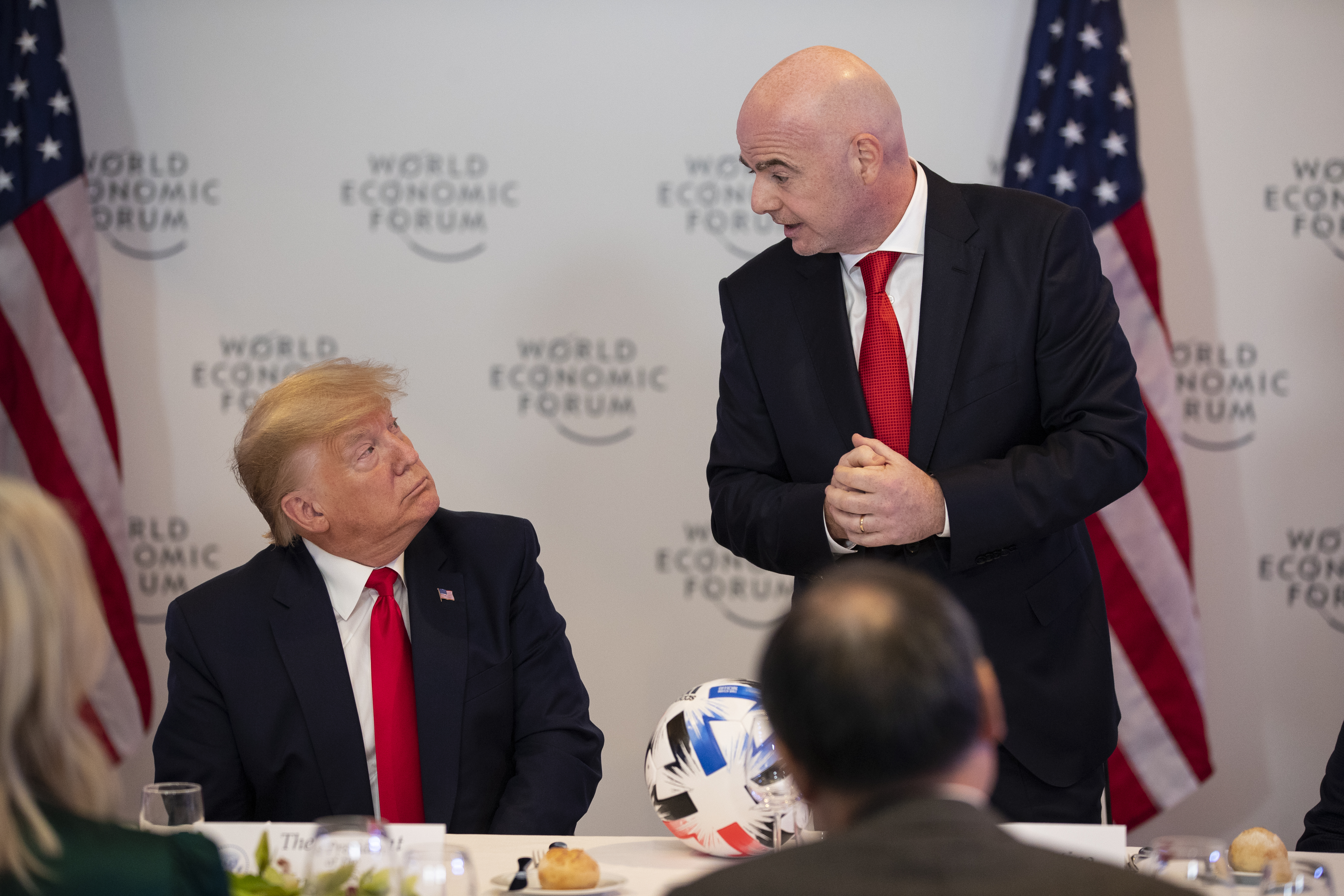 Donald Trump listens as Gianni Infantino speaks.