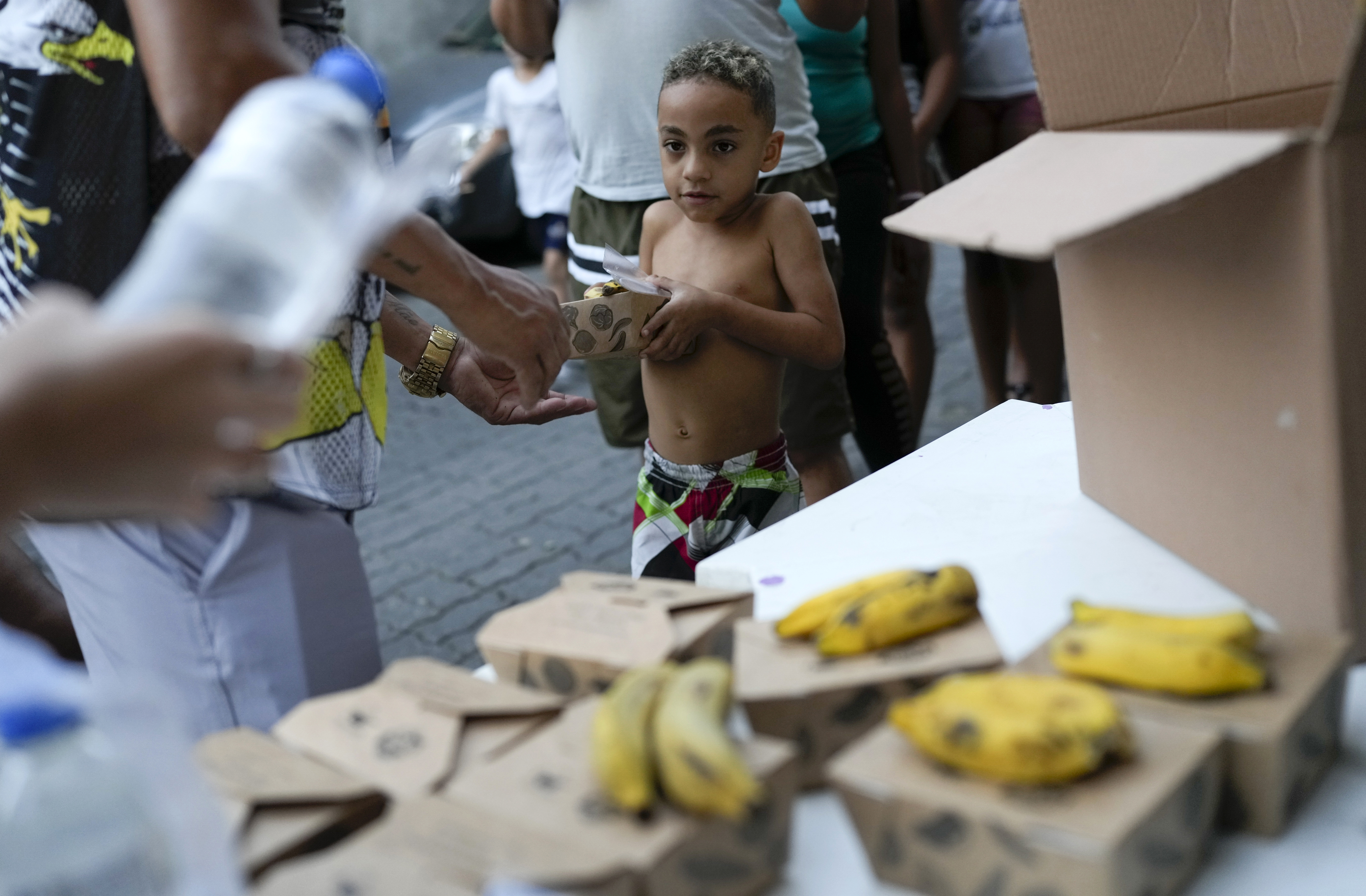A boy gets food donated by a social project at Turano favela, Rio de Janeiro, Monday, June 17, 2024. According to a study by the Federal University (UFRJ) and the City Council of Rio, there are more than 2 million inhabitants in the city of Rio de Janeiro living with some level of food insecurity. (AP Photo/Silvia Izquierdo)