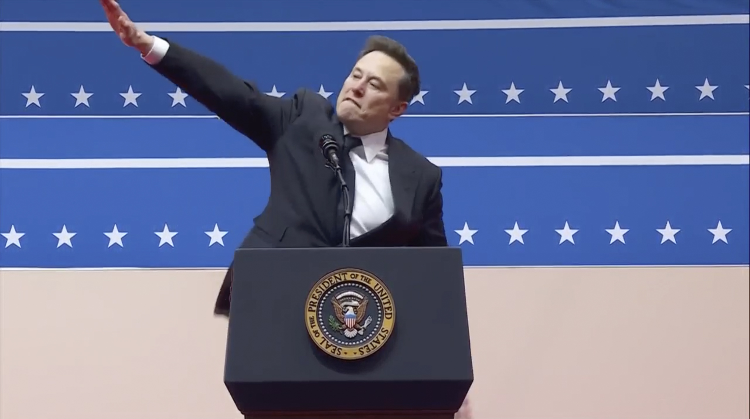 Elon Musk makes a gesture with his arm extended at the Capitol One Arena