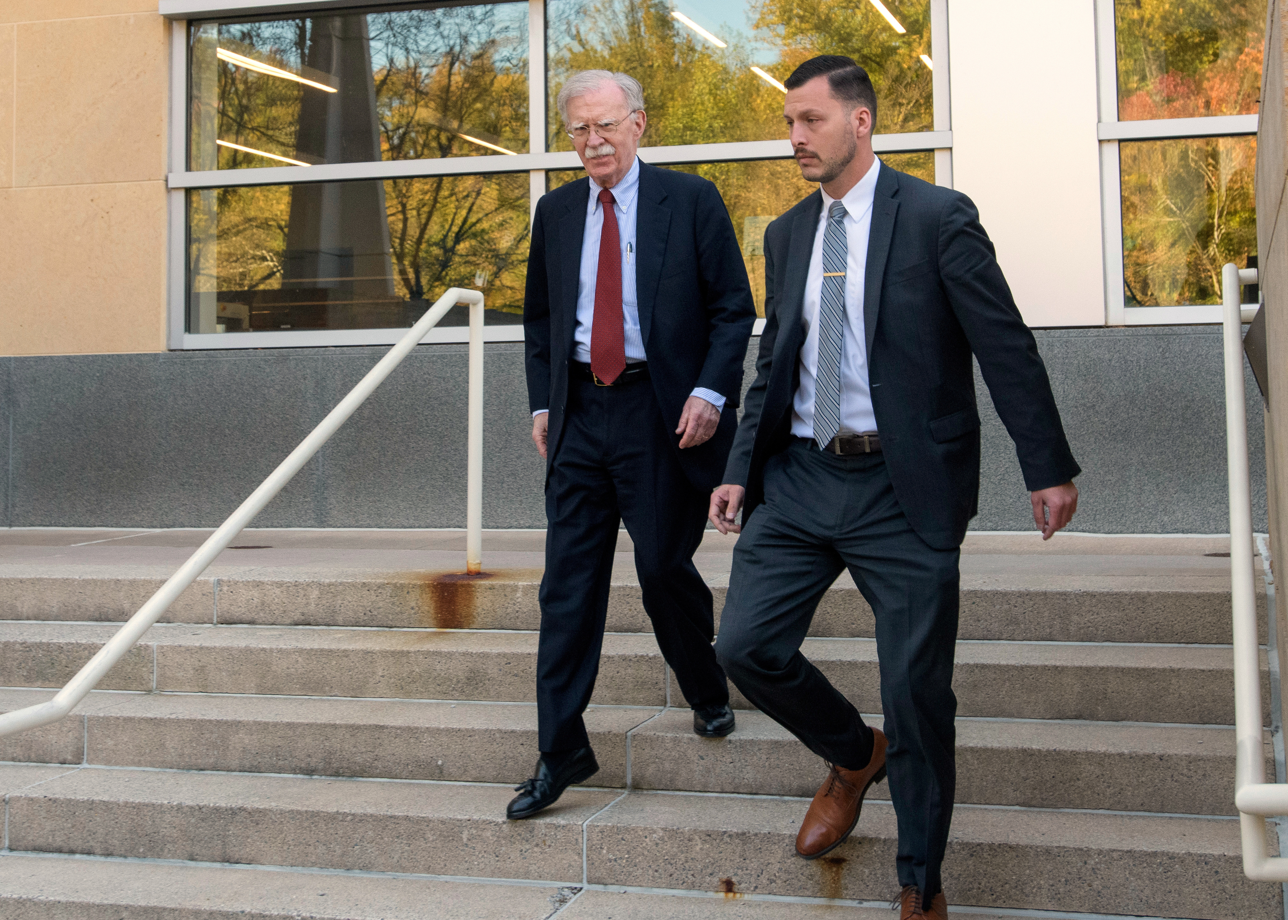 John Bolton and his lawyer walk down courthouse steps.
