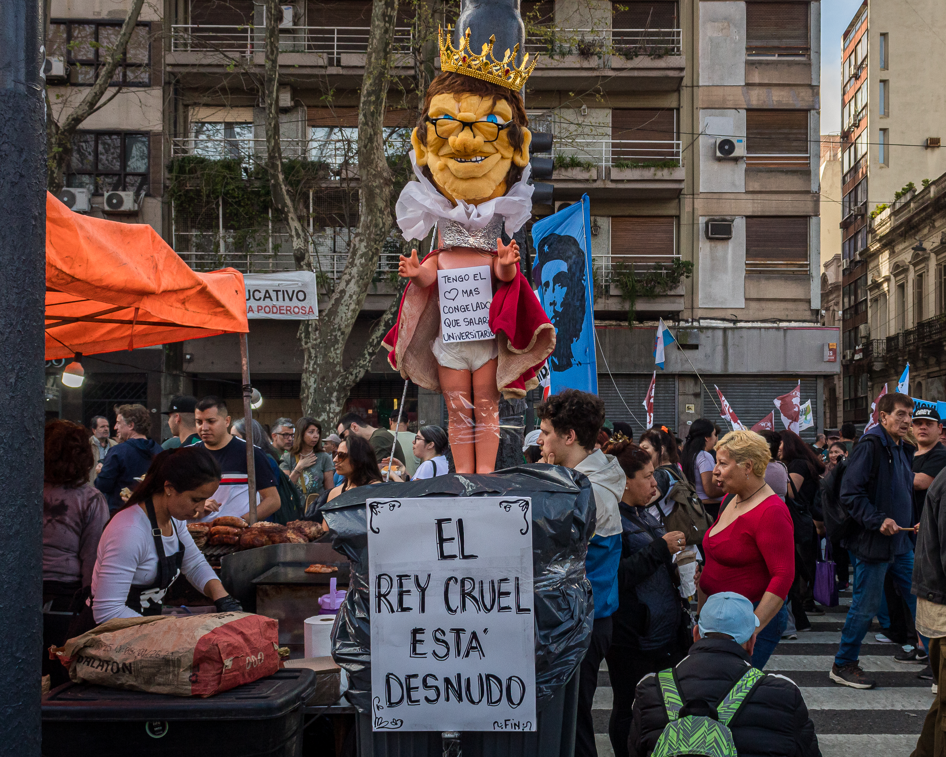 An effigy of Javier Milei as a king is displayed above a protest sign on the streets of Argentina that reads in Spanish,