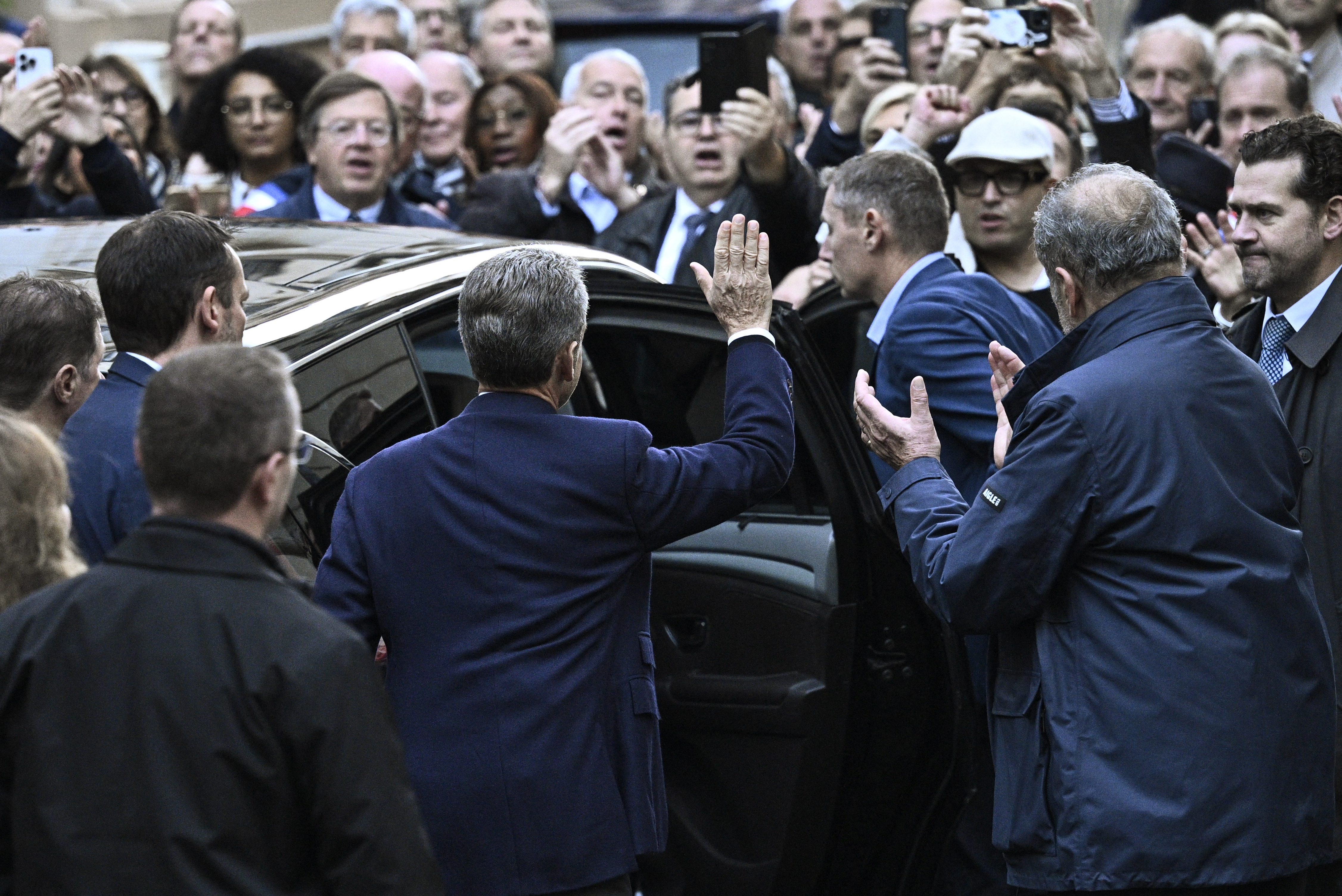 France's former president Nicolas Sarkozy (C) waves to his supporters as he leaves his residence to present himself to La Sante Prison for incarceration on a five-year prison sentence after being convicted of criminal conspiracy over a plan for late Libyan dictator Moamer Kadhafi to fund his 2007 electoral campaign, in Paris, on October 21, 2025.