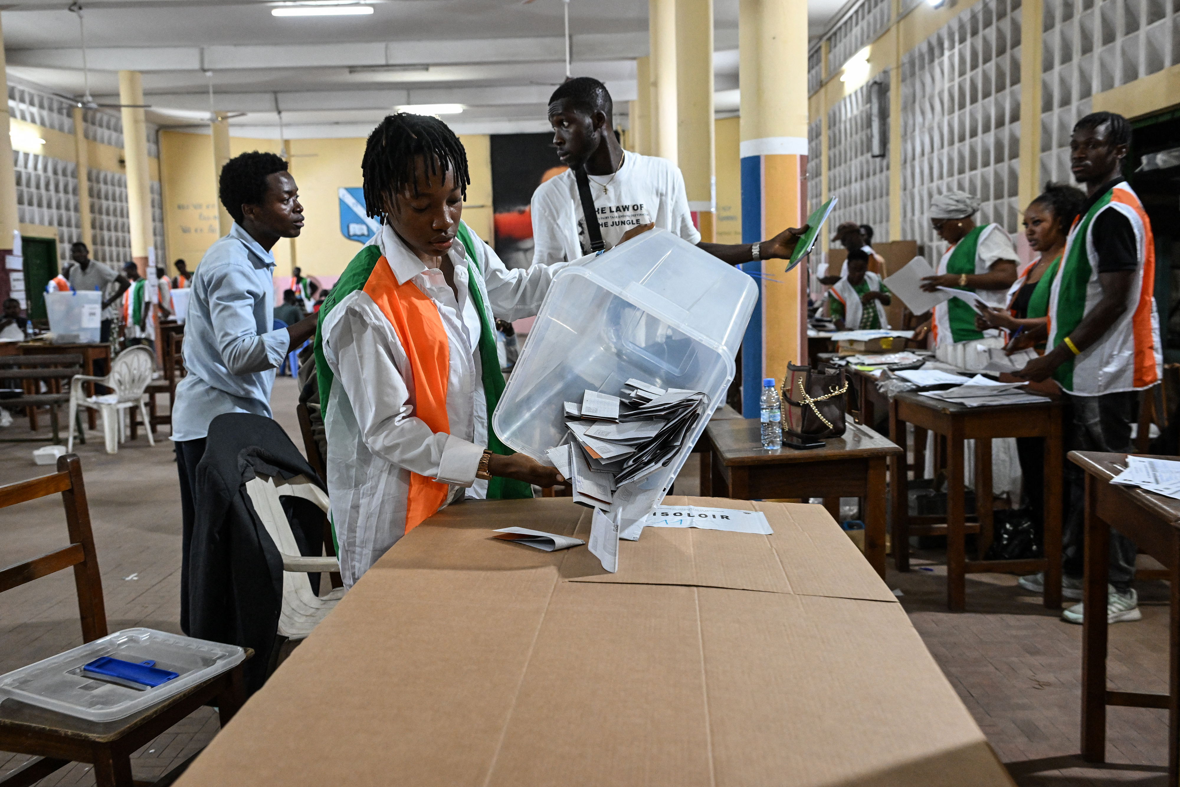 An Independent Electoral Commission of Ivory Coast (CEI) official empties a ballot box as they count votes at the Notre-Dame College, in Plateau, the business district of Abidjan, on October 25, 2025 after polls closed during Ivory Coast's presidential elections.