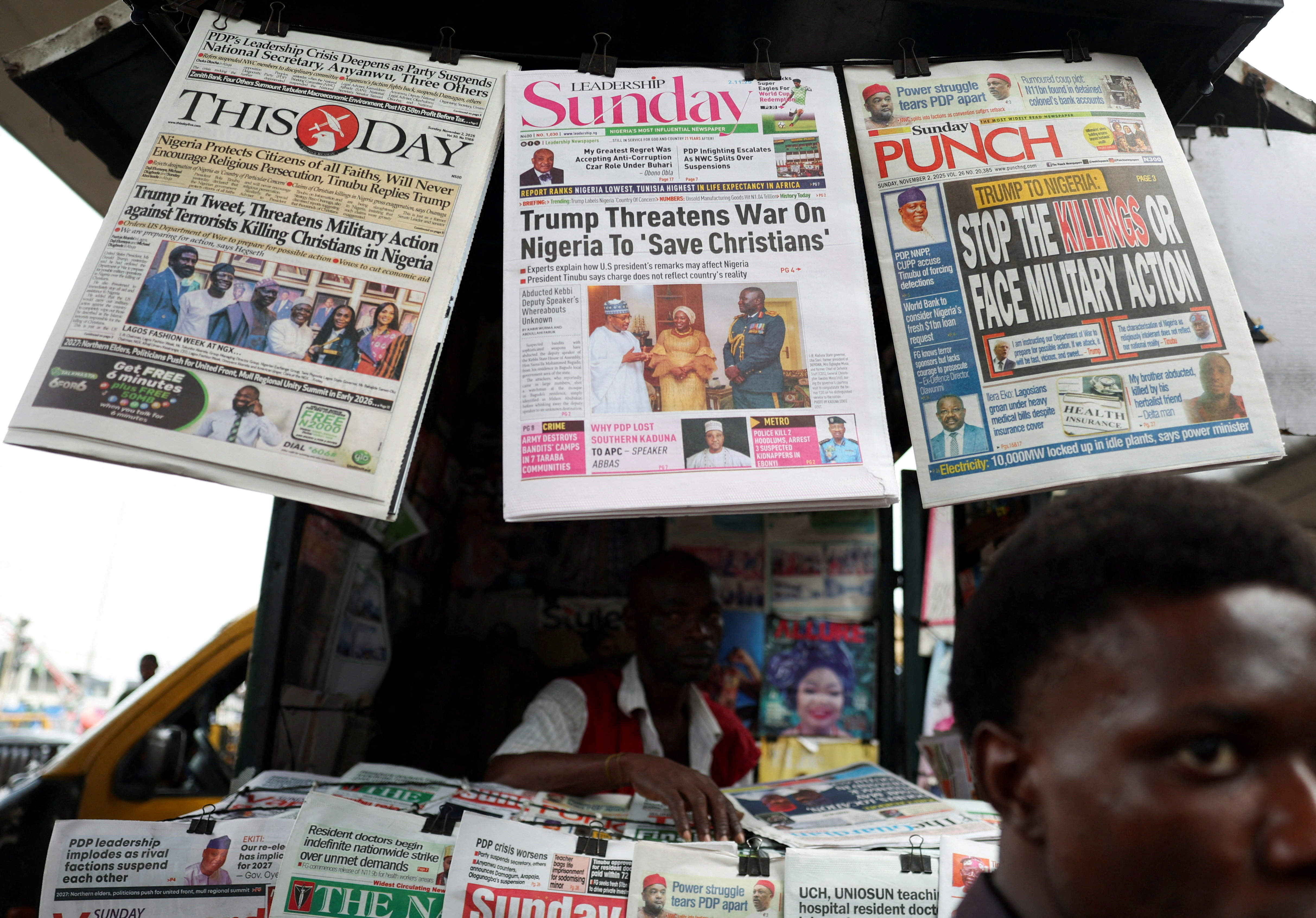 Newspapers with articles reporting U.S. President Donald Trump's message to Nigeria over the treatment of Christians hang at a newspaper stand in Ojuelegba, Lagos, Nigeria November 2, 2025 [Sodiq Adelakun/Reuters]