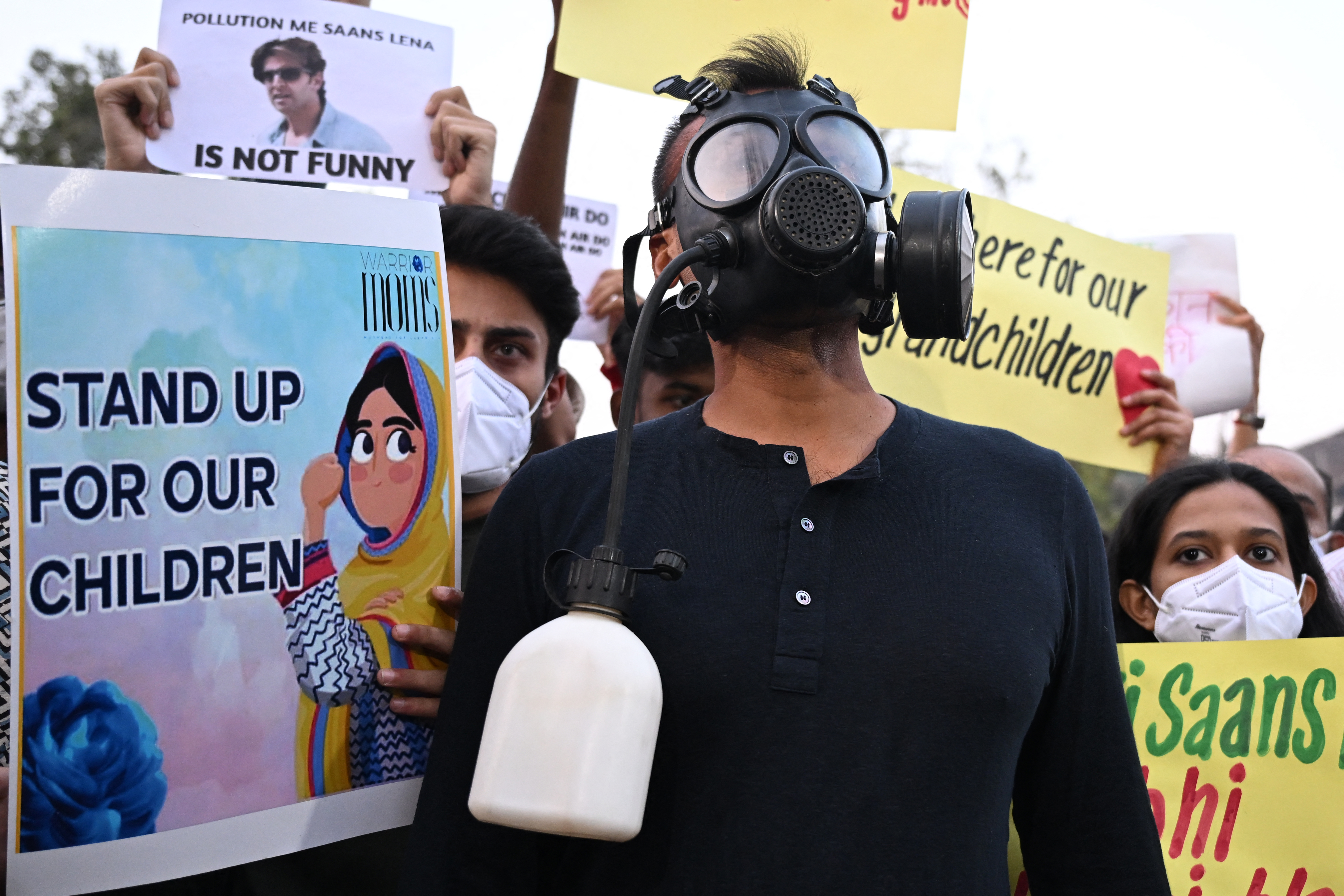 Demonstrators wearing masks hold posters during a protest.