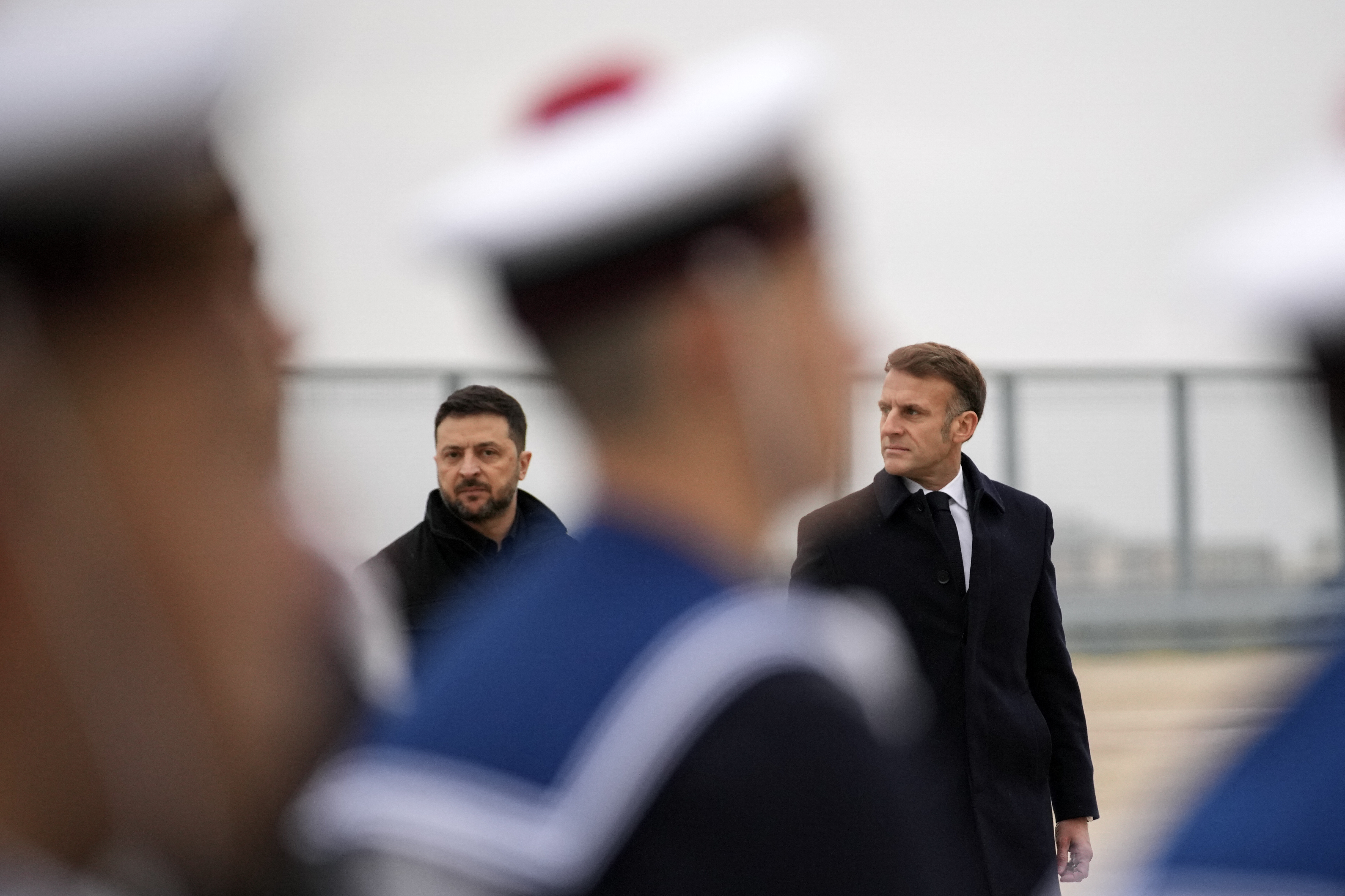 France's President Emmanuel Macron (R) and Ukraine's President Volodymyr Zelensky (L) review the troops at the Villacoublay air base, in Velizy-Villacoublay, near Paris on November 17, 2025. Ukraine's President visits Paris on November 17, in a new bid to secure weaponry to defend his country against increasingly lethal Russian missile and drone attacks. His visit is part of a brief tour of his western allies. (Photo by Christophe Ena / POOL / AFP)