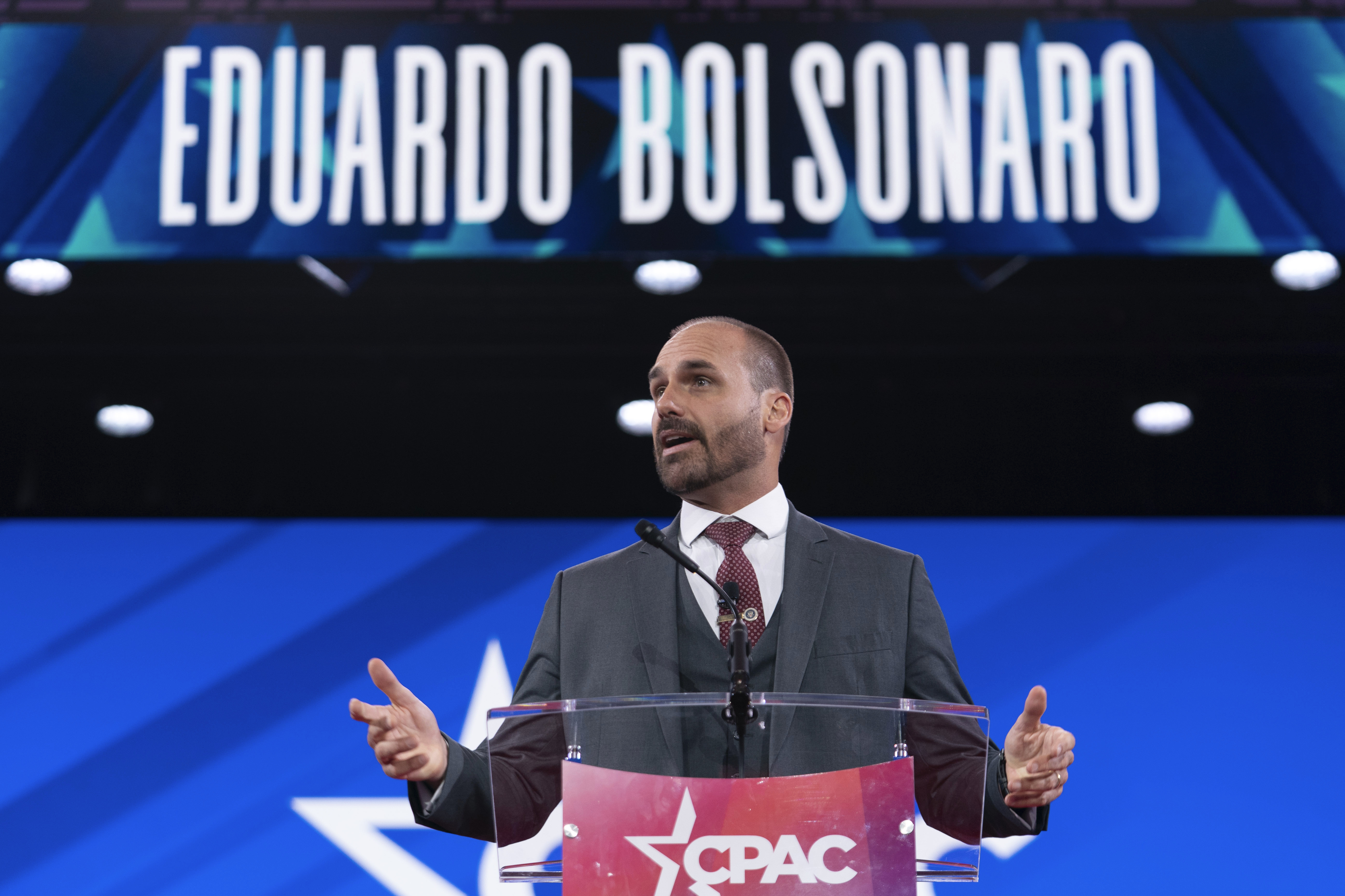 Eduardo Bolsonaro speaks at a podium under a sign for his name.