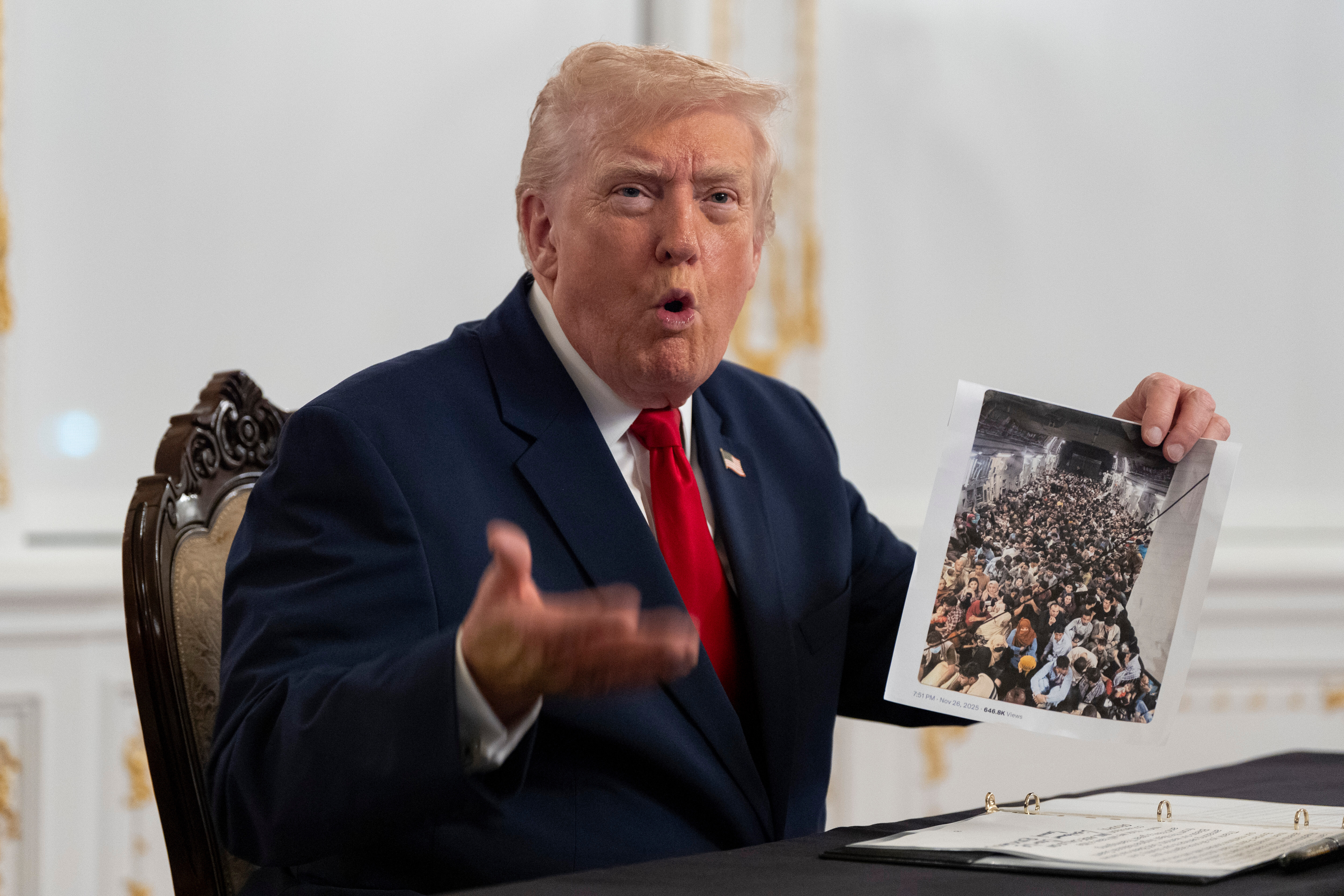 Trump holds up a photo of Afghan refugees
