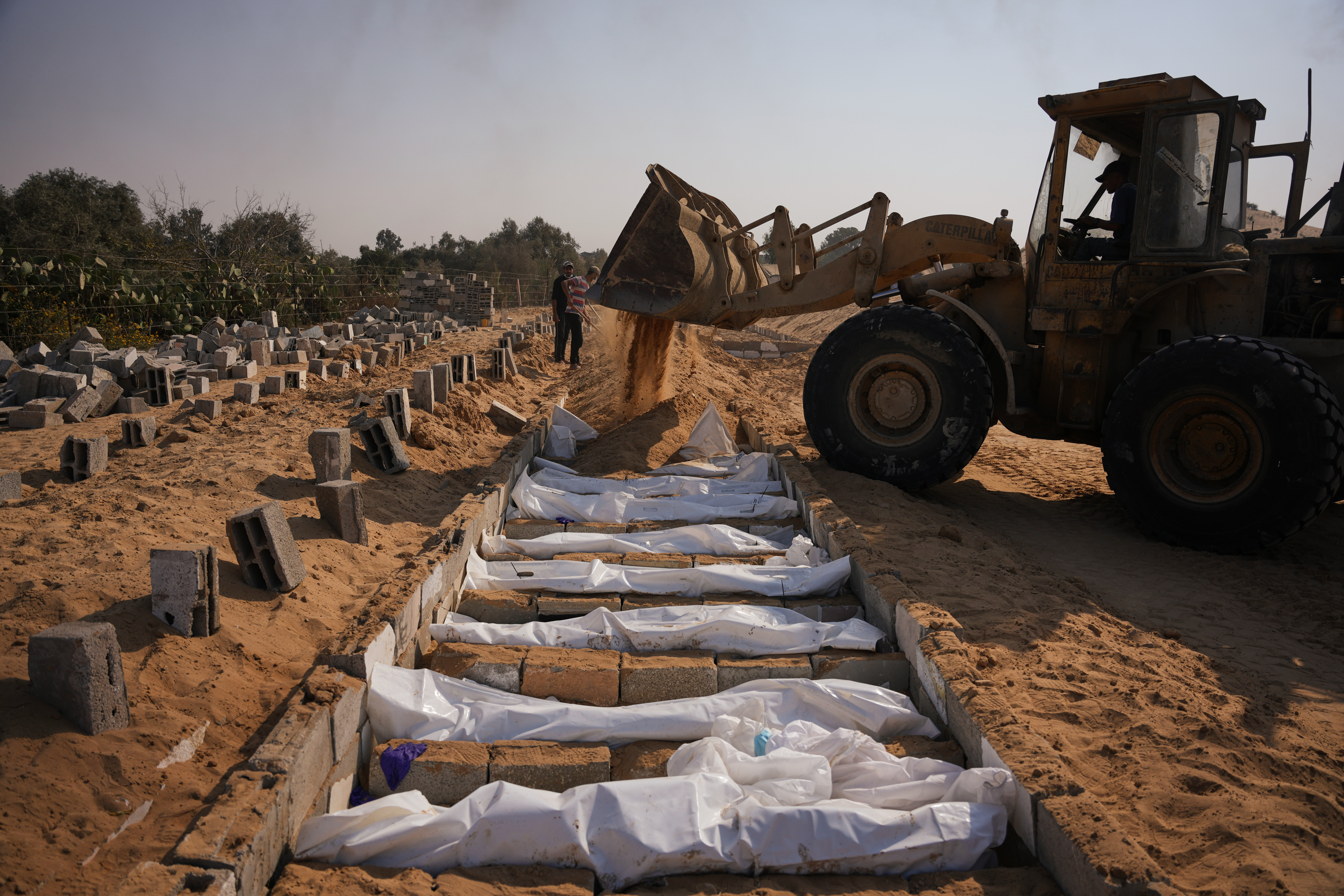 Bodies of unidentified Palestinians returned from Israel as part of the ceasefire deal are buried in a mass grave in Deir al-Balah, Gaza Strip, Wednesday, Nov. 5, 2025. (AP Photo/Abdel Kareem Hana)