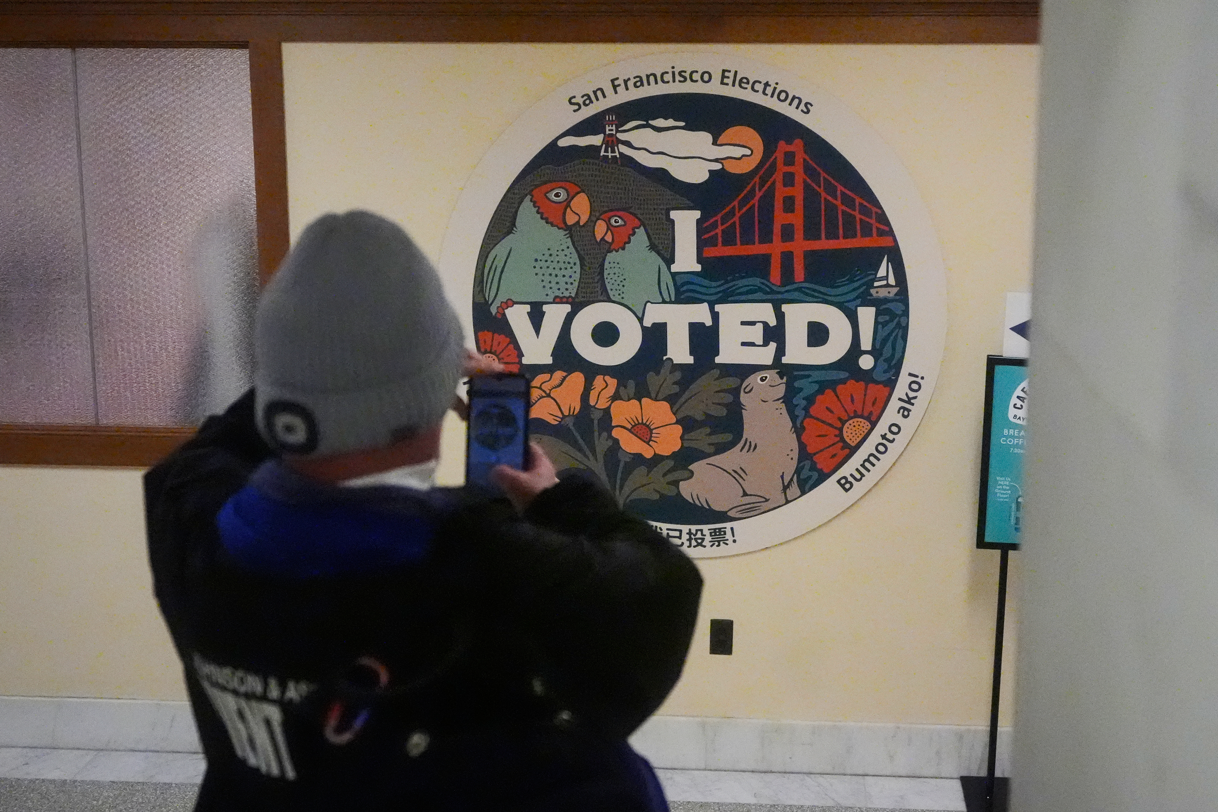 A voter takes a photo of an election sign on Tuesday, Nov. 4, 2025, in San Francisco. (AP Photo/Jeff Chiu)
