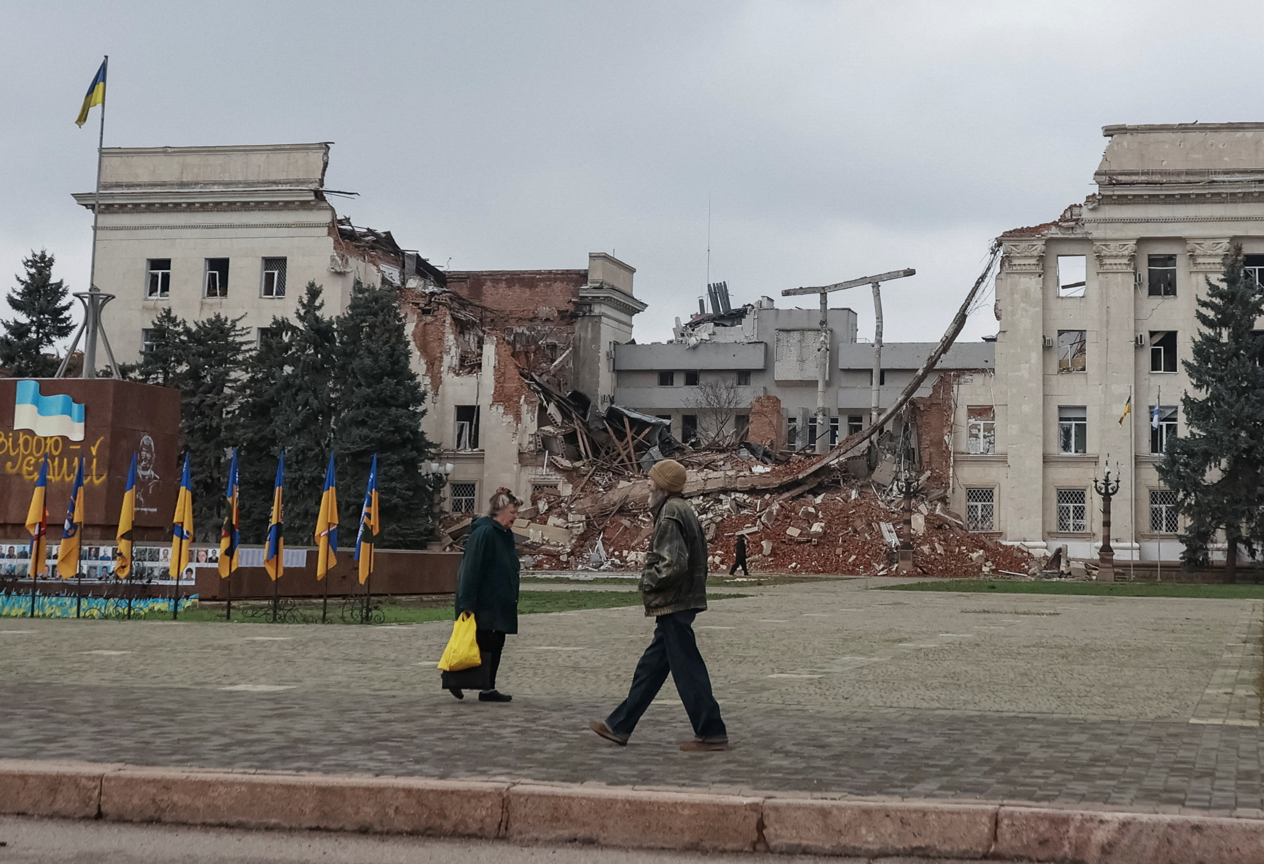 People walk near a building hit during a Russian military strike, amid Russia's attack on Ukraine, in the frontline city of Kherson, Ukraine November 11, 2025. REUTERS/Nina Liashonok