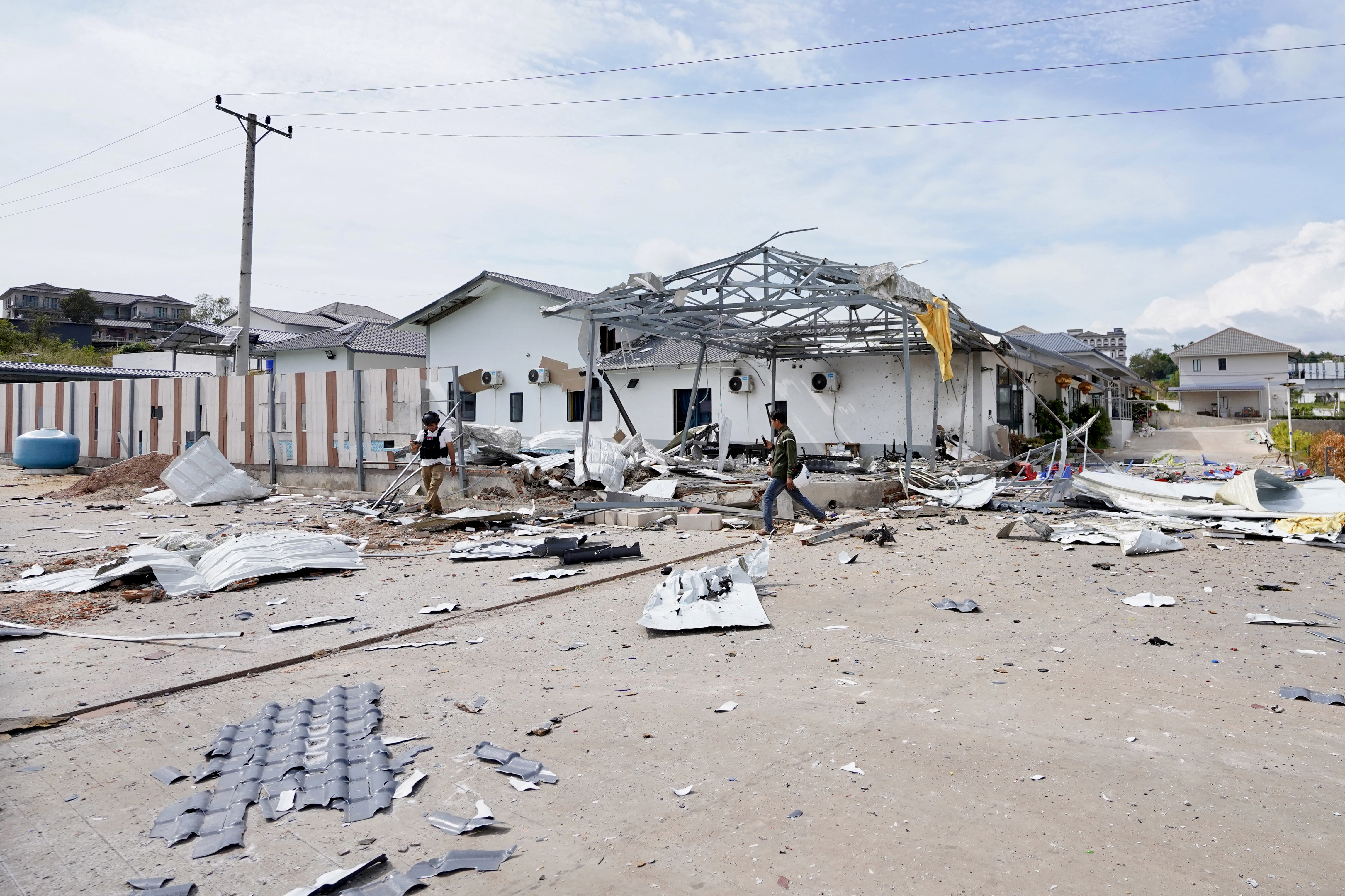 Men looking at a damaged house.