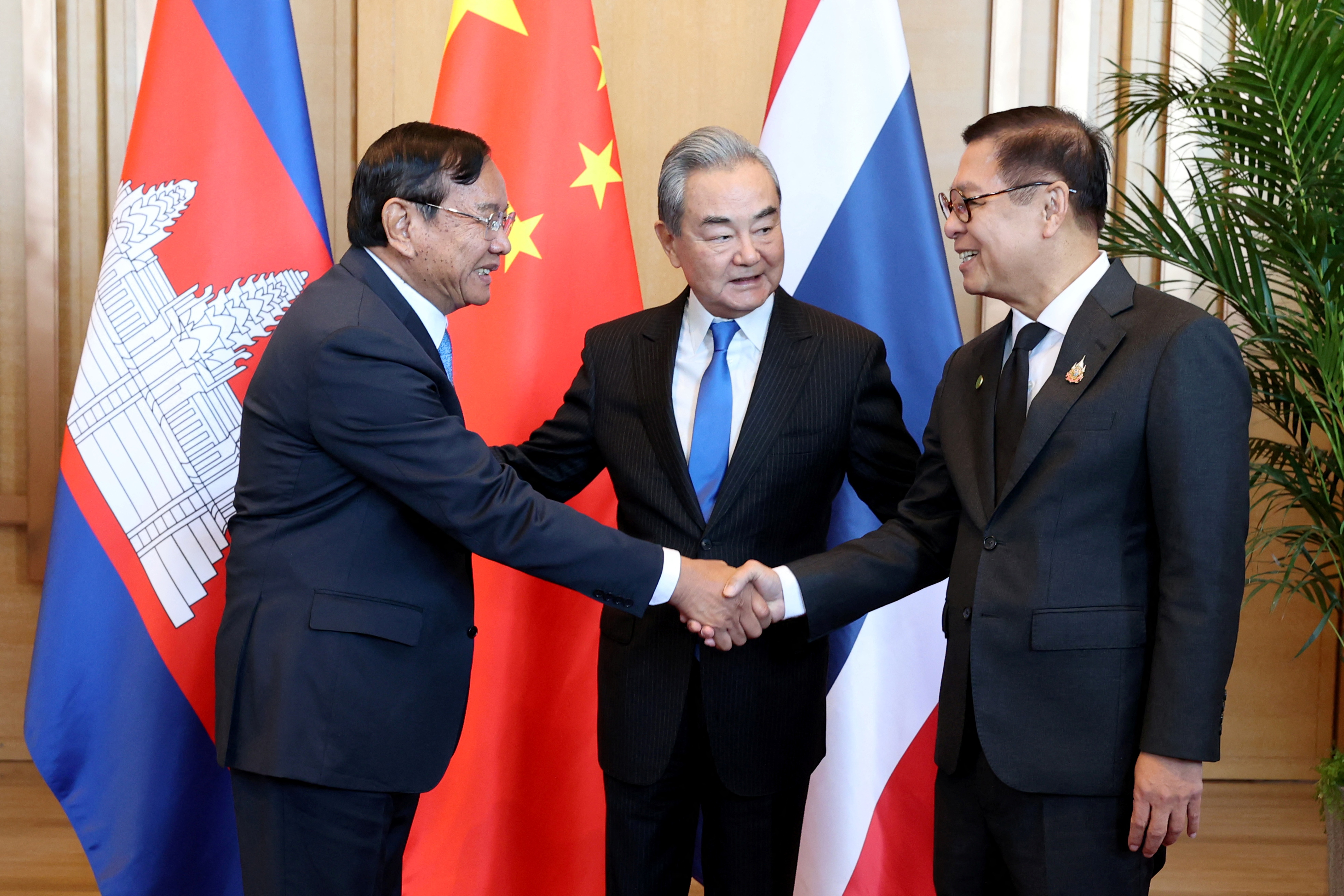 China's Foreign Minister Wang Yi (C) looks on as Cambodia's Deputy Prime Minister Prak Sokhonn (L), who is also the country's Foreign Minister, shakes hands with Thailand's Foreign Minister Sihasak Phuangketkeow (R) during a meeting in China's Yunnan province.