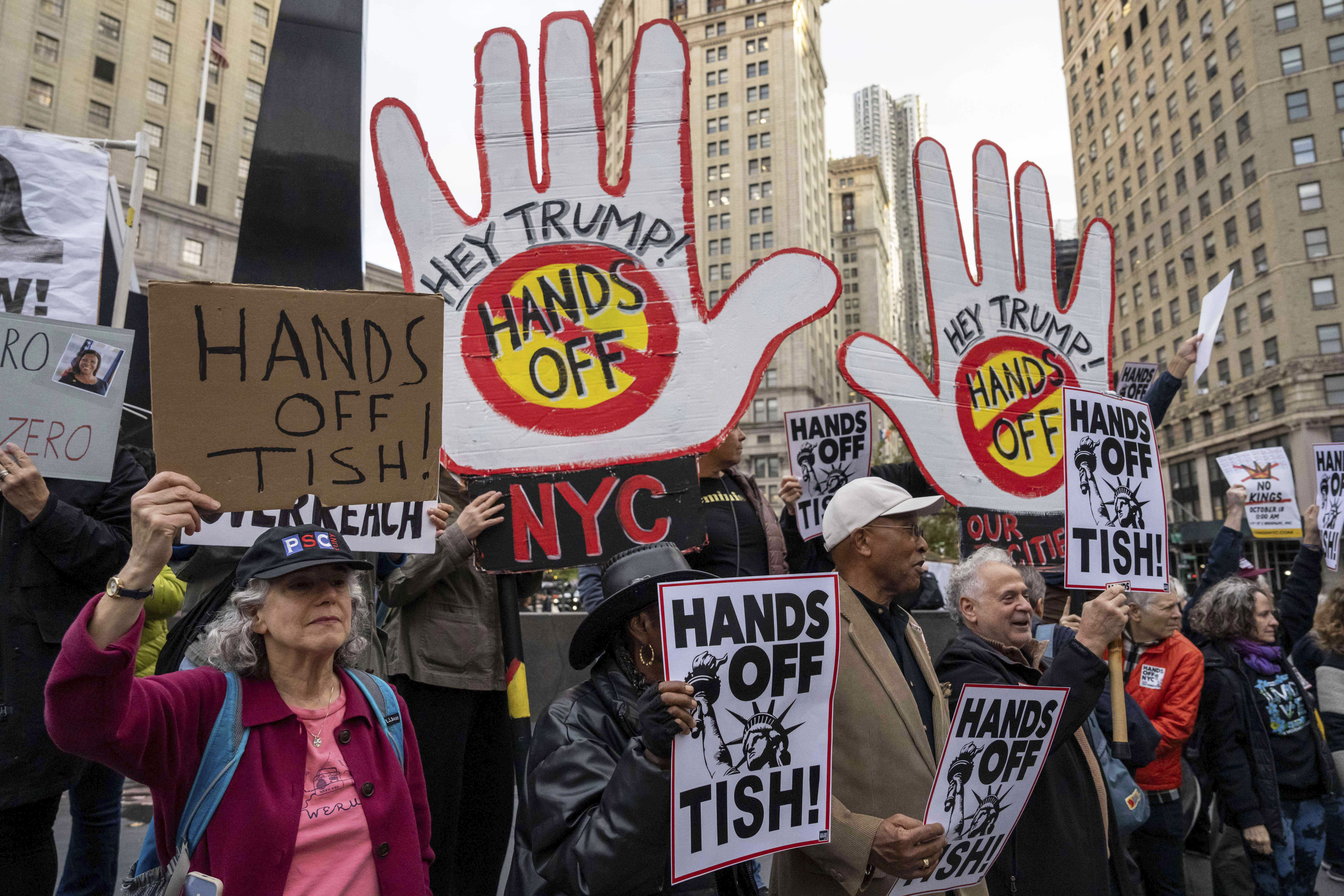 Protesters in New York hold up signs that read "Hey Trump, hands off" and "Hands off Tish!"