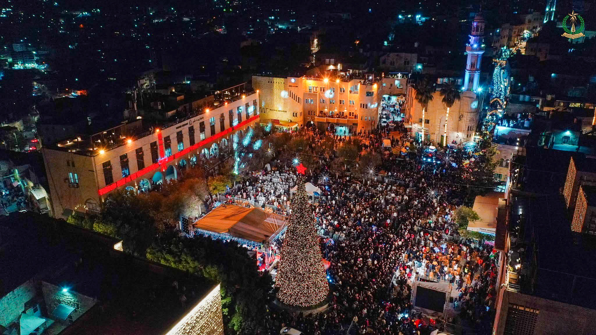 Crowds at night around the lit Christmas tree.