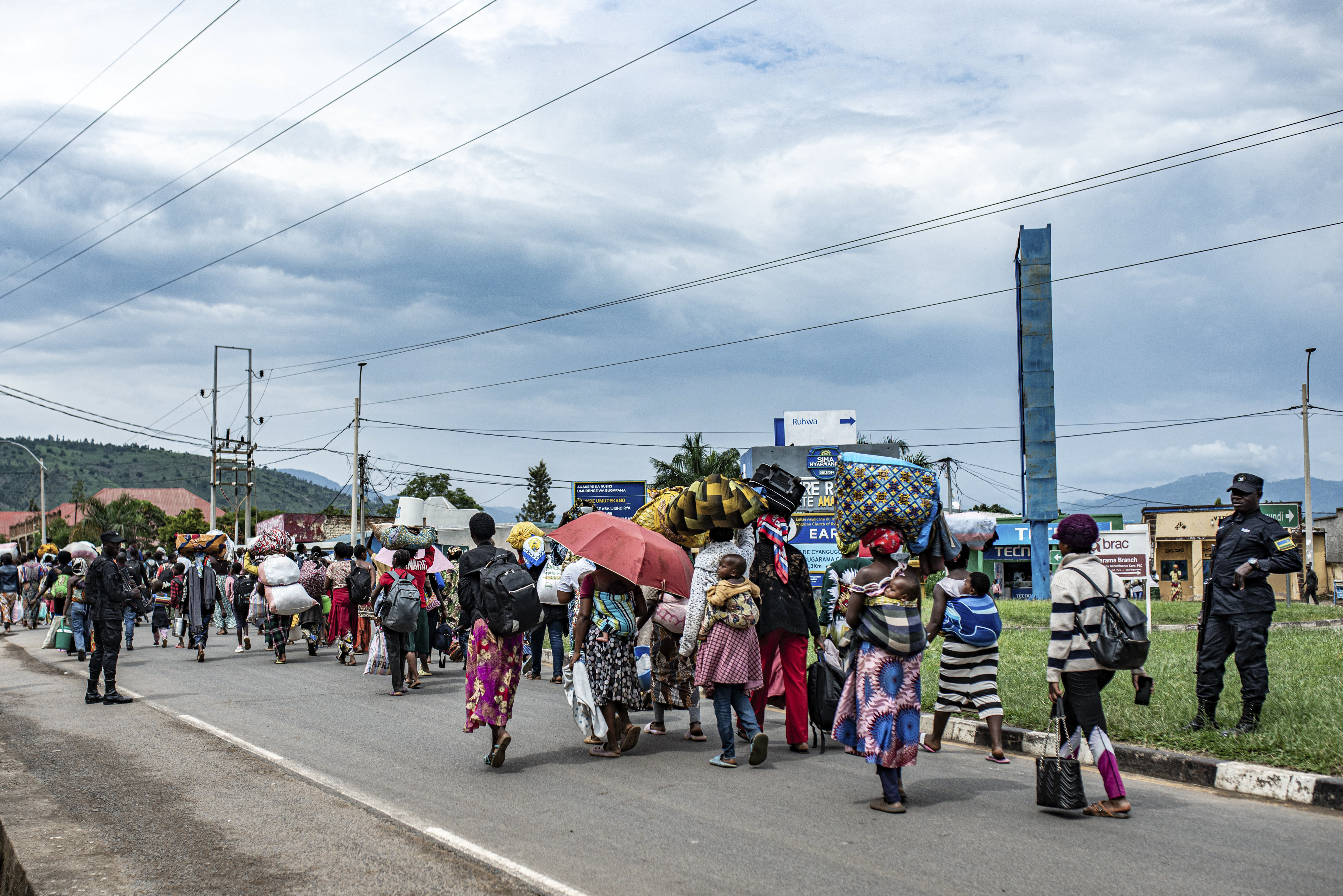 Rwandan soldiers accompany a group of displaced people from the DR Congo in Bugarama as they arrive in Rwanda after fleeing intense shelling