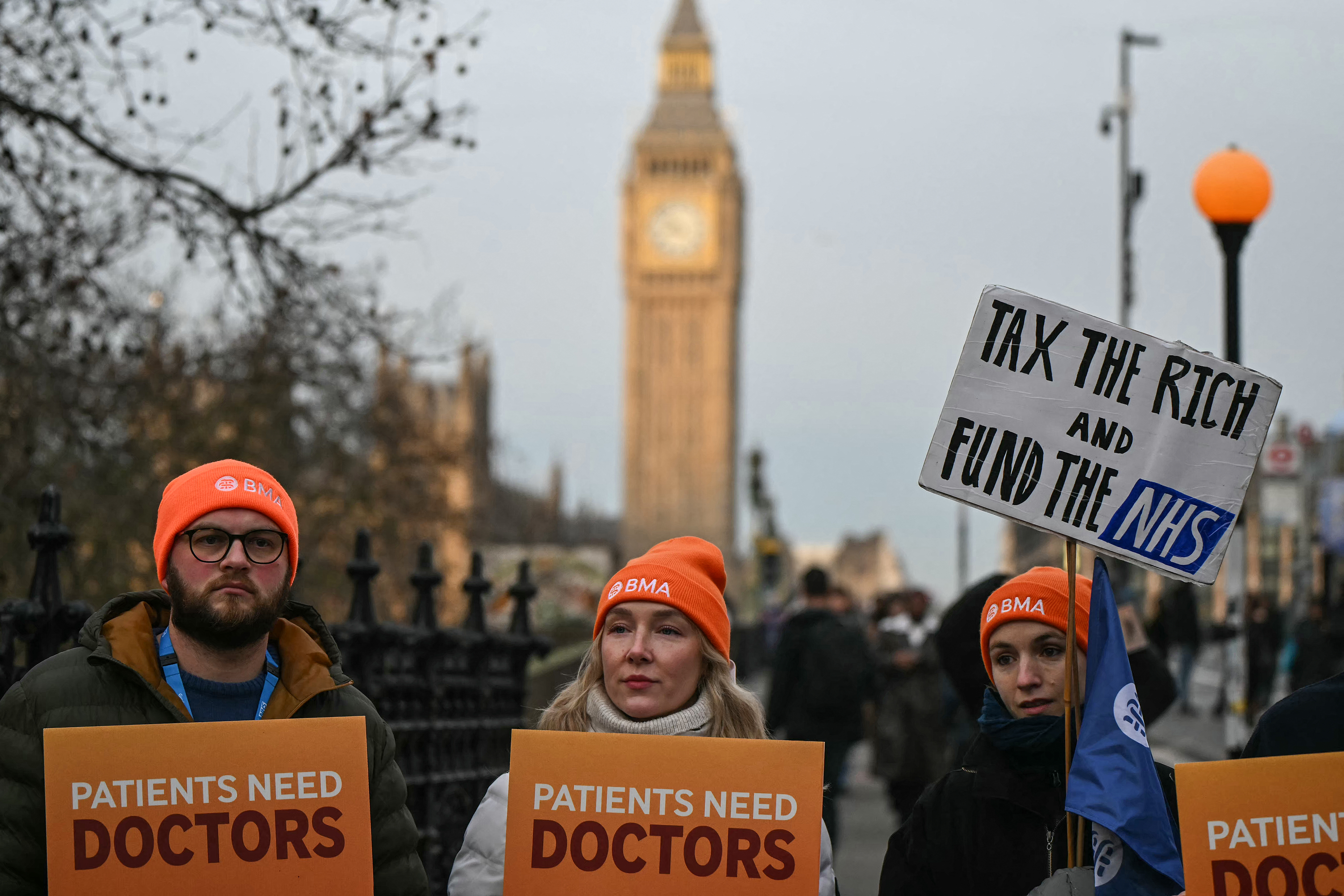 Staff members hold placards as they stand on a picket line during the first day of a five-day resident doctors' strike outside St Thomas' Hospital in central London on December 17, 2025.