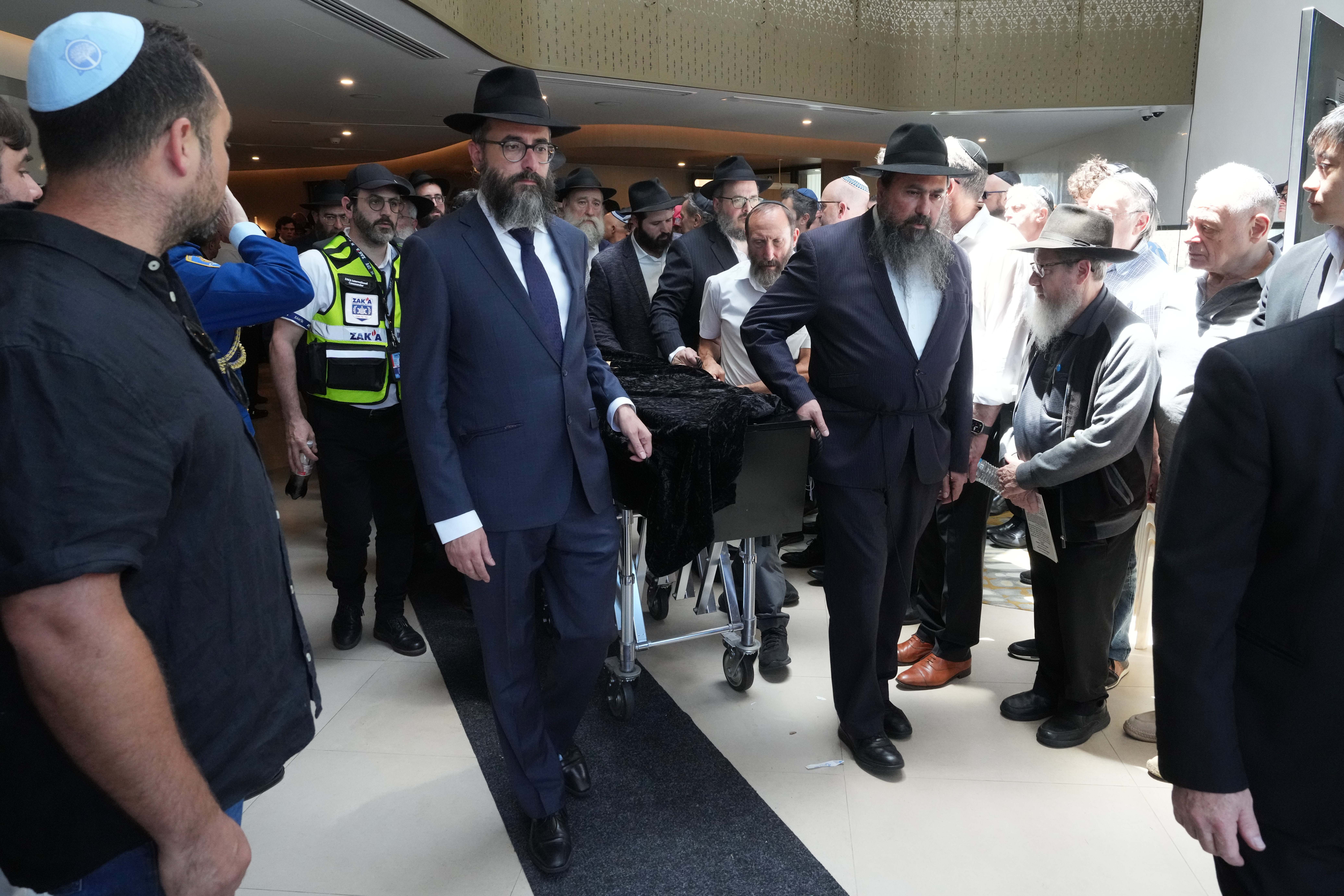 The coffin of Rabbi Eli Schlanger, a victim in the Bondi Beach mass shooting, is escorted out of a synagogue after his funeral service in Bondi on Wednesday, Dec. 17, 2025, in Sydney, Australia. (AP Photo/Mark Baker, Pool)