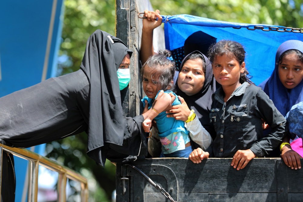 Rohingya refugees disembark a truck after being forcibly relocated from South Aceh to the Banda Aceh, Indonesia