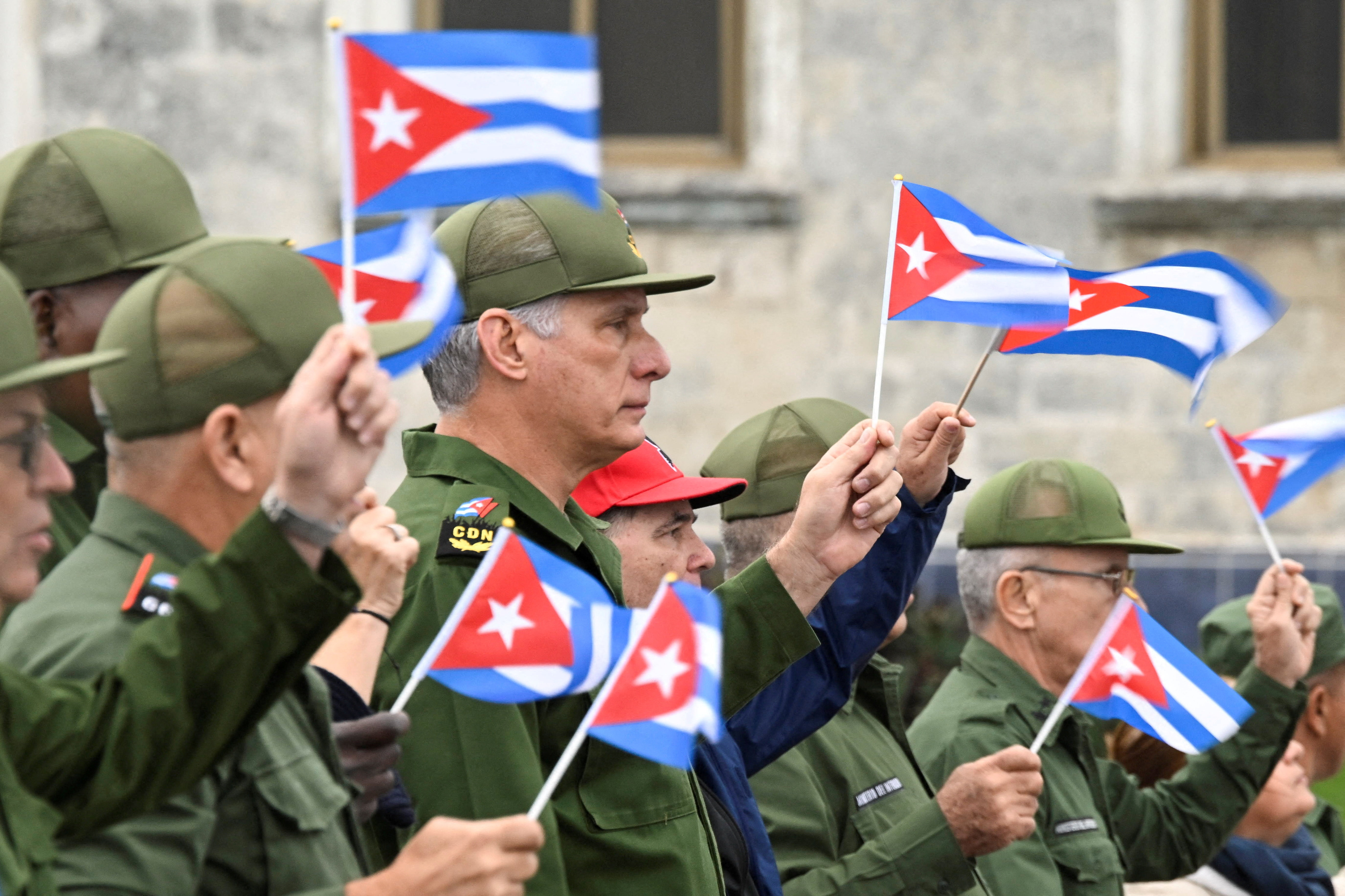 Men in green uniforms wave Cuban flags
