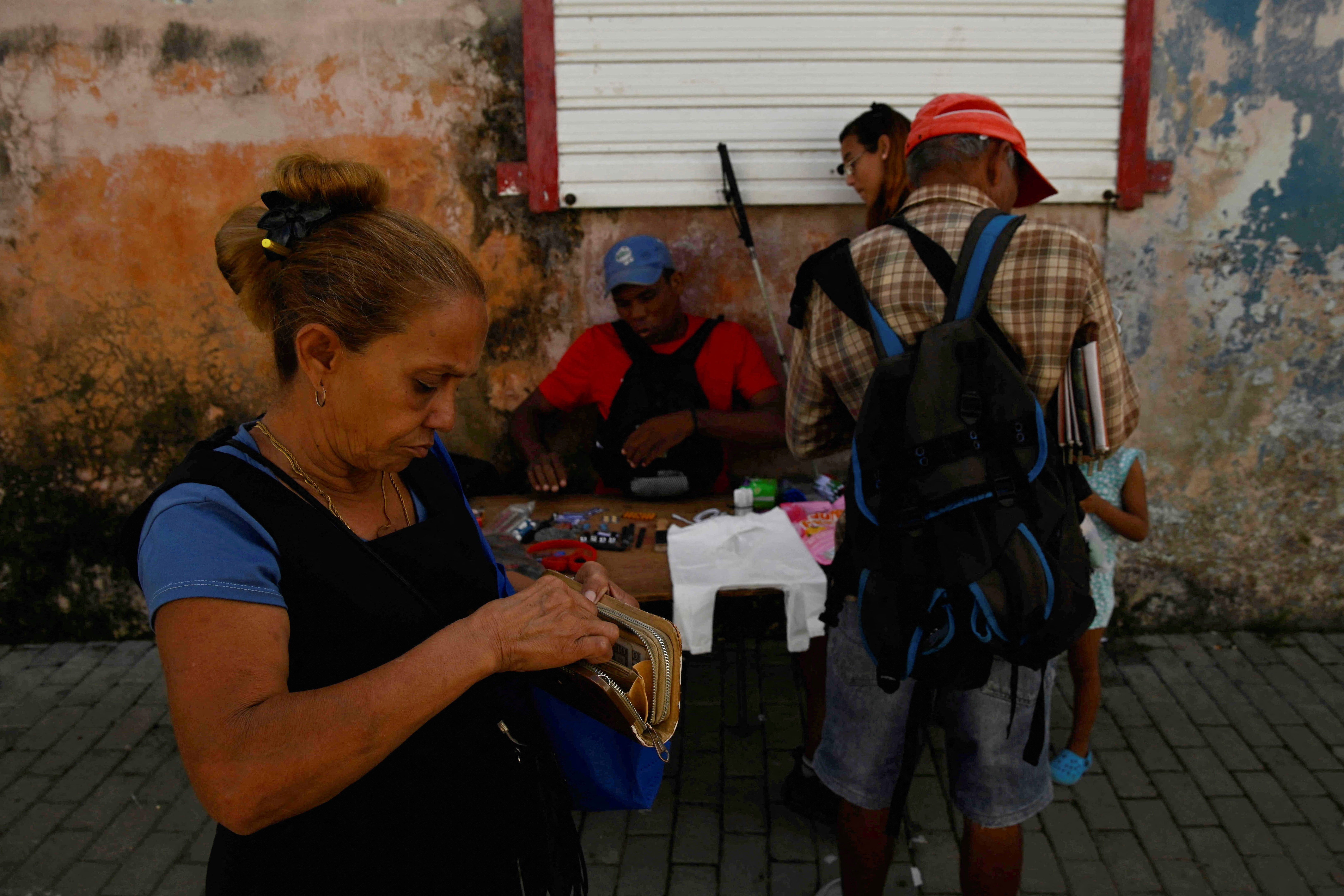 A woman counts money to buy goods from a street vendor in Havana