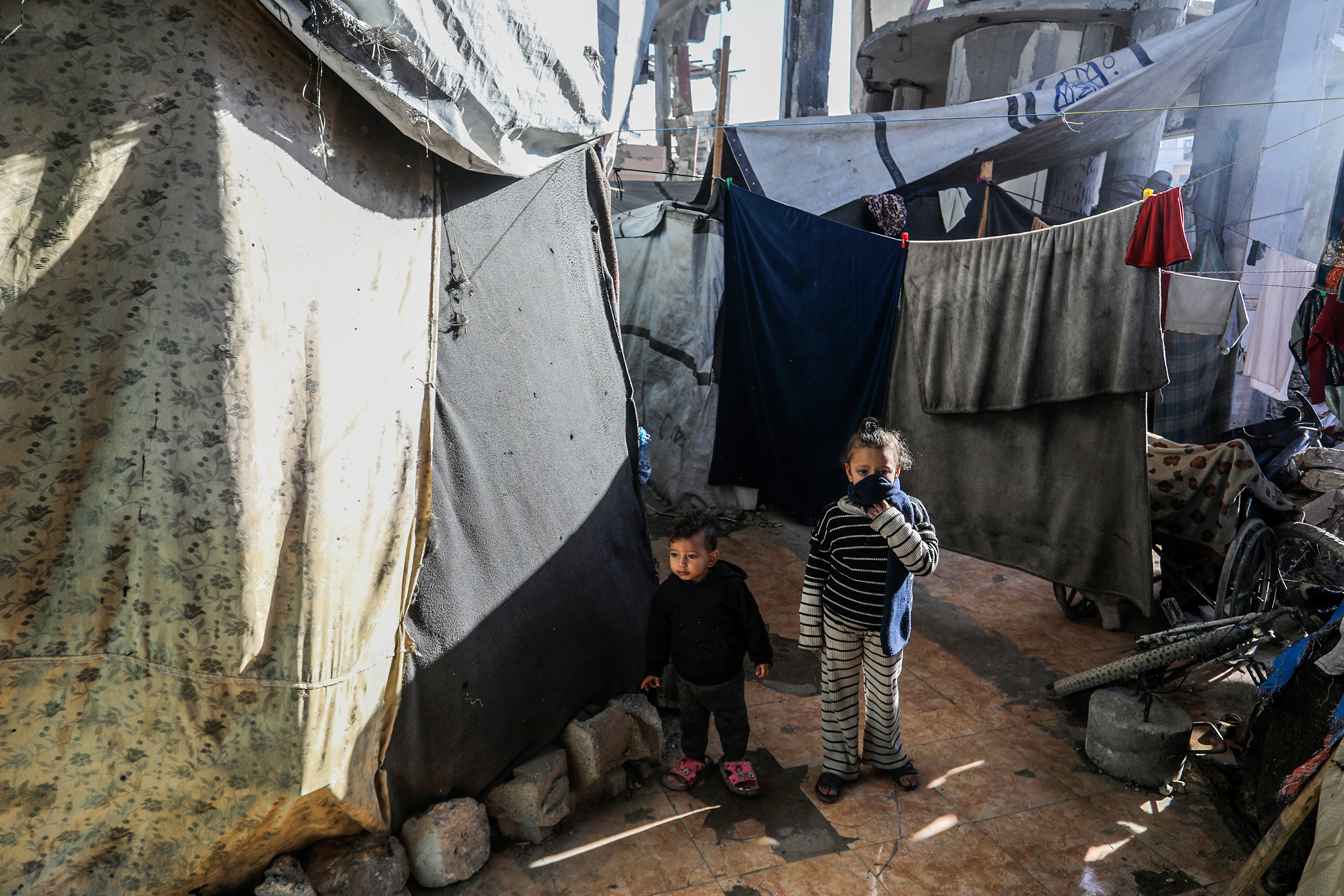 Families living in makeshift tents with blankets hung up between them.
