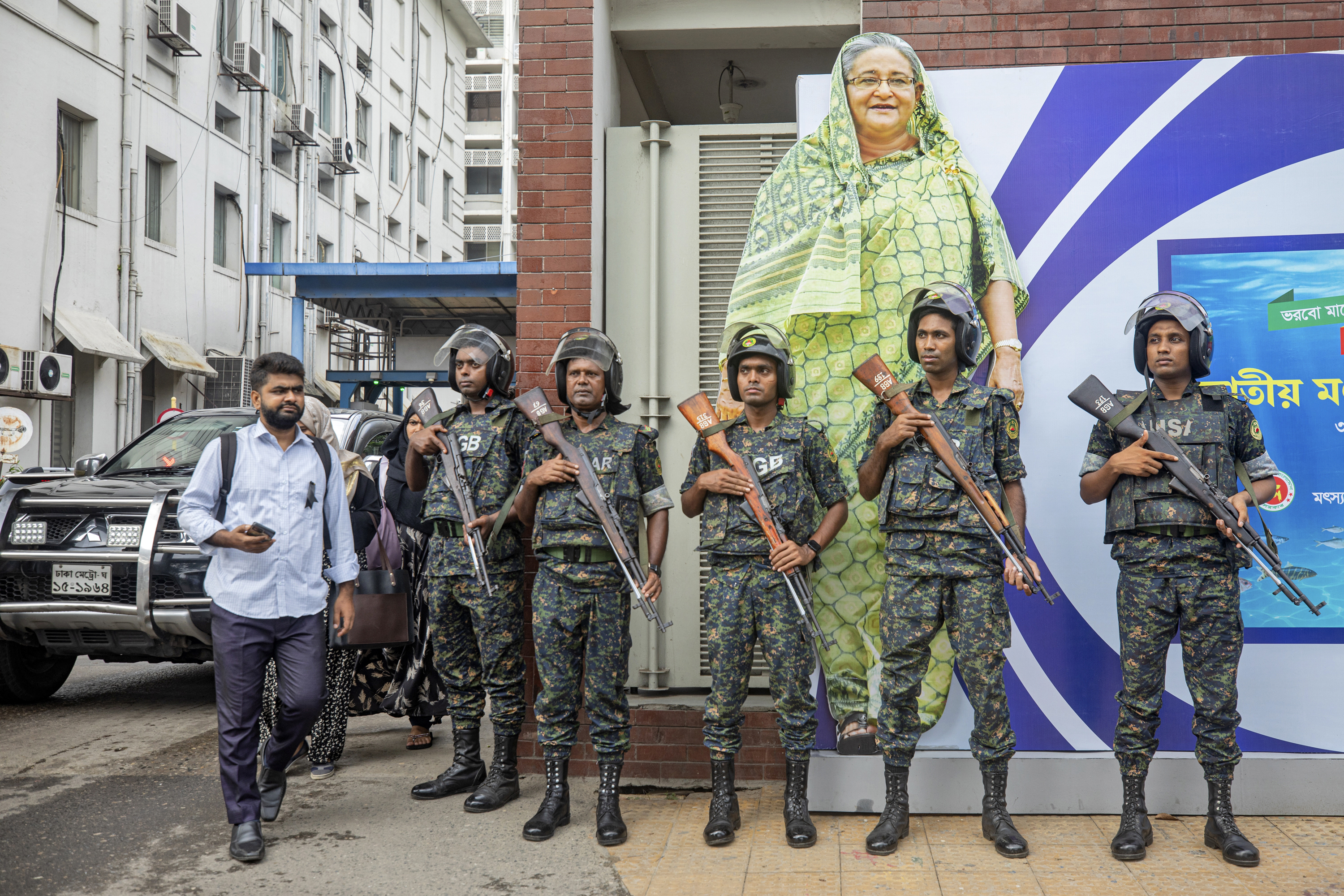 FILE - Military personnel stand in front of a portrait of Prime Minister Sheikh Hasina in Dhaka, Bangladesh, on July 30, 2024, during a national day of mourning to remember the victims of recent deadly clashes. (AP Photo/Rajib Dhar, File)