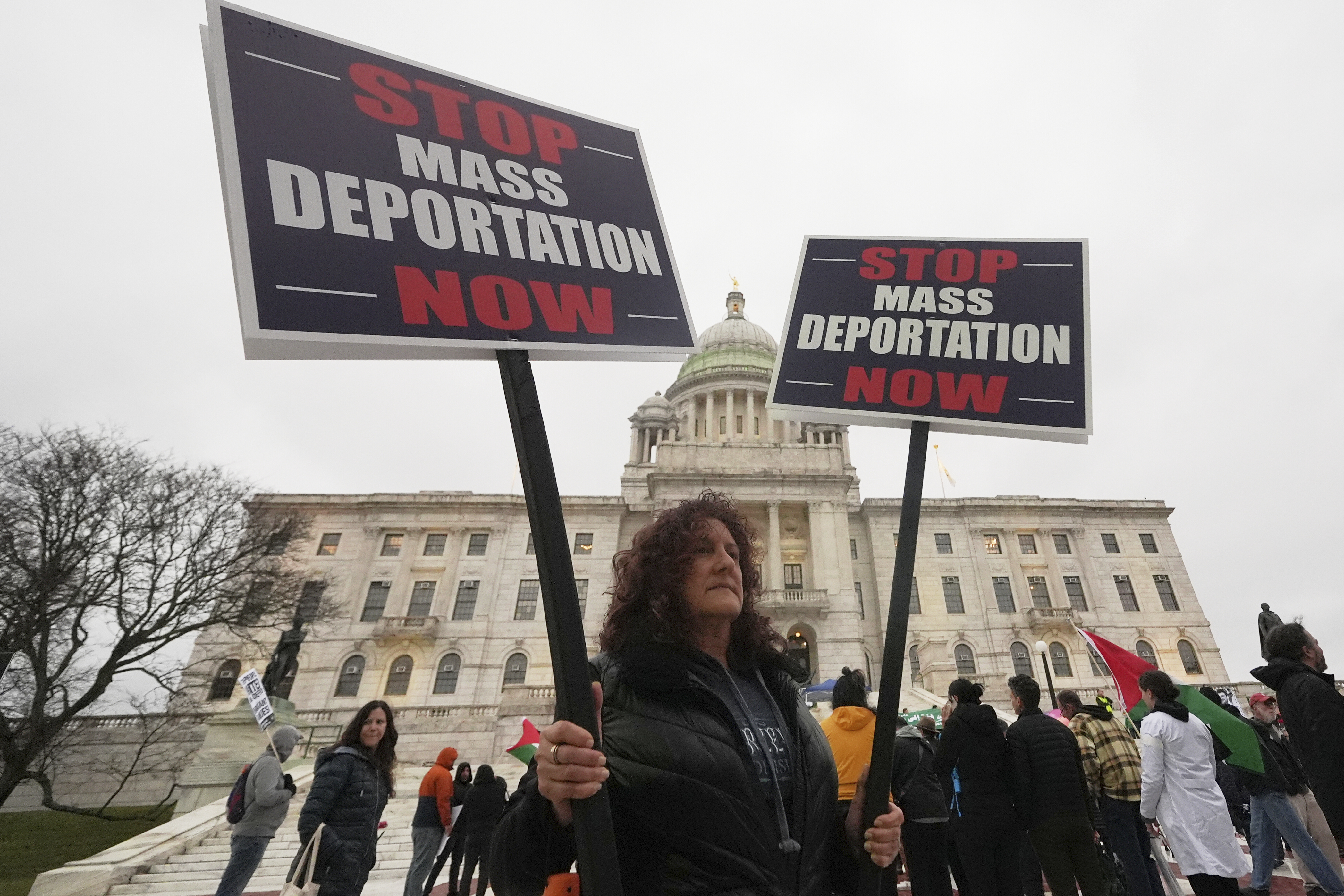 A protester holds up a sign that says, "Stop Mass Deportation Now"
