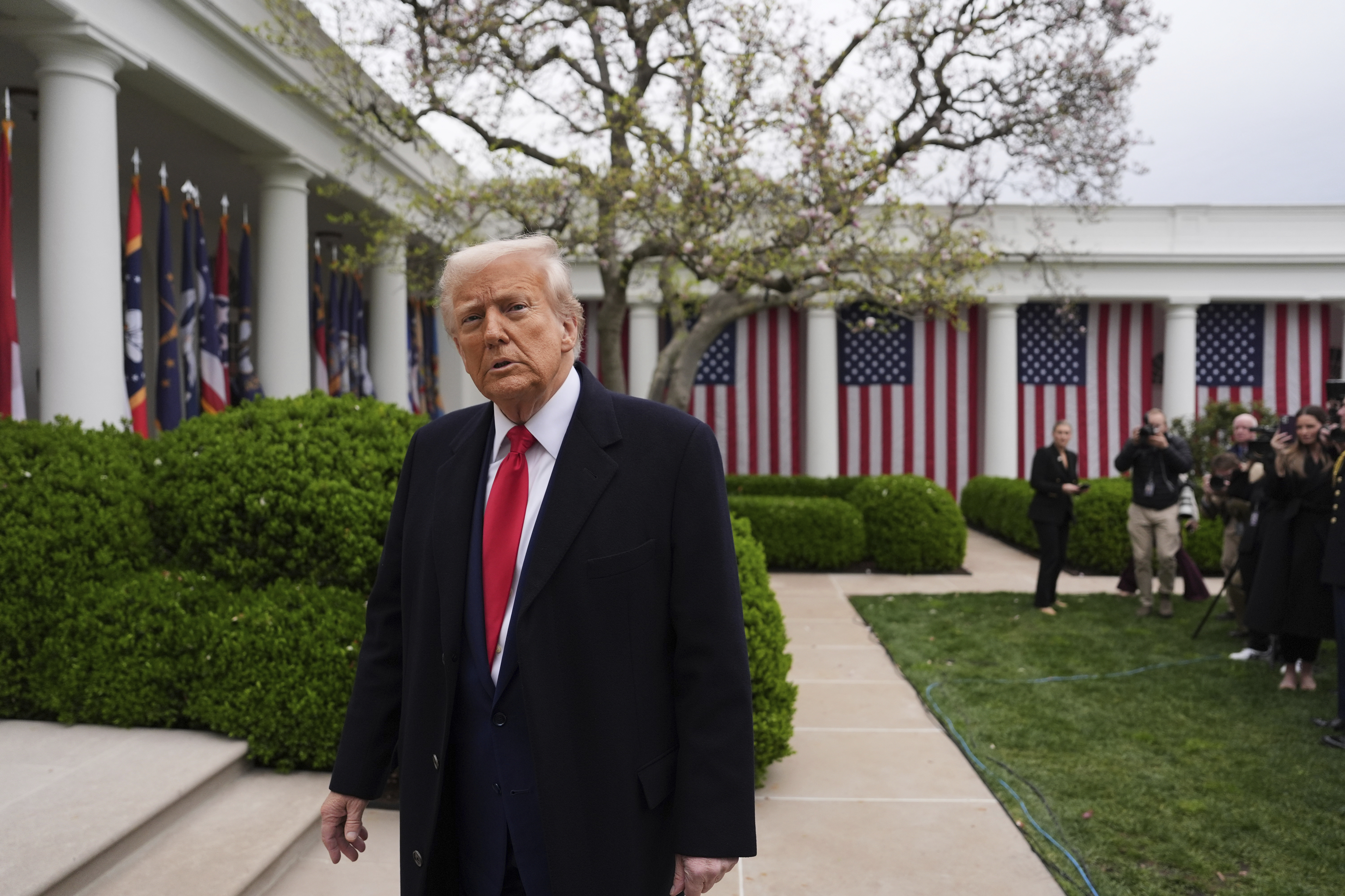 Donald Trump walks through a flag-lined Rose Garden