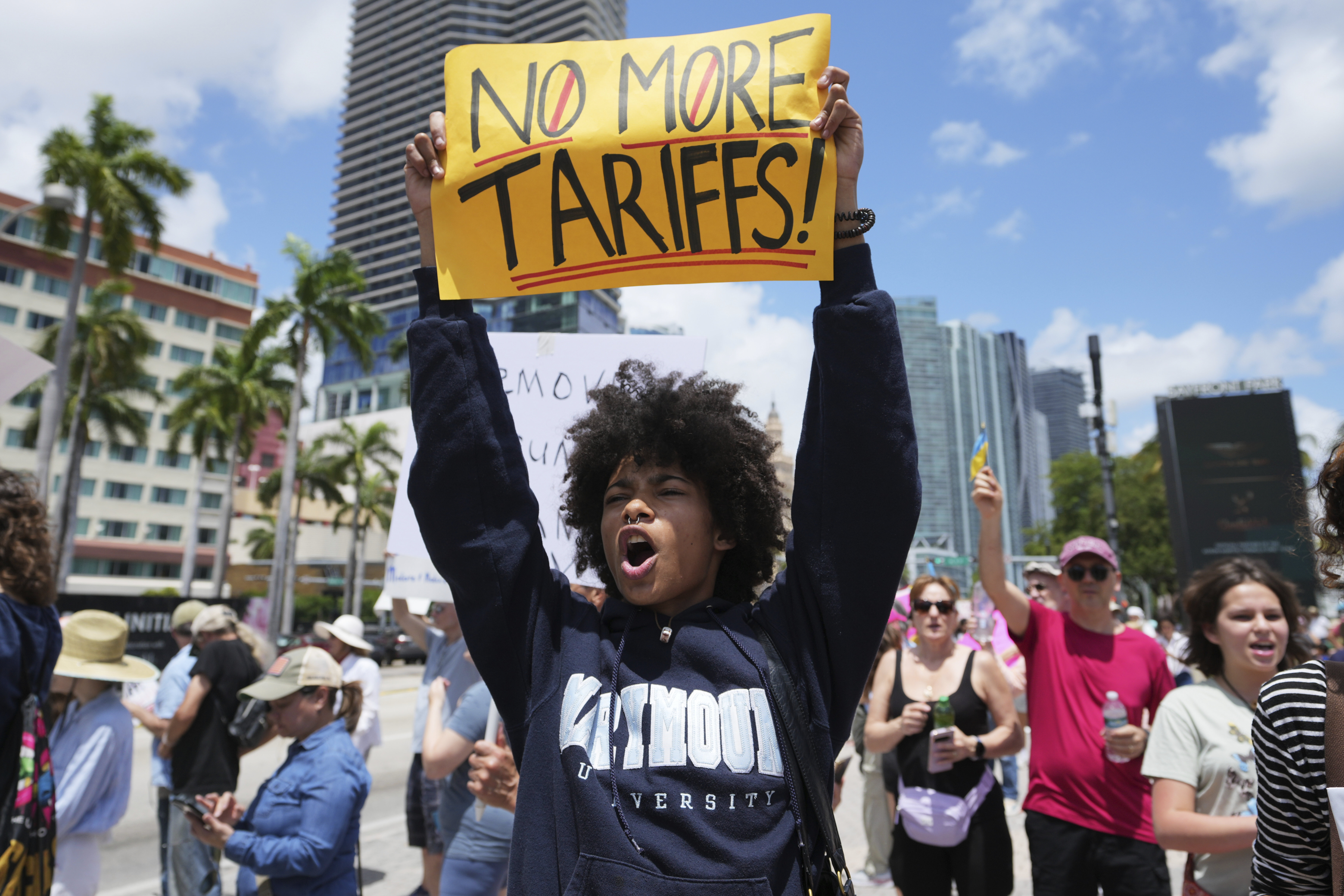 A protester holds up a sign that reads, "No More Tariffs!"