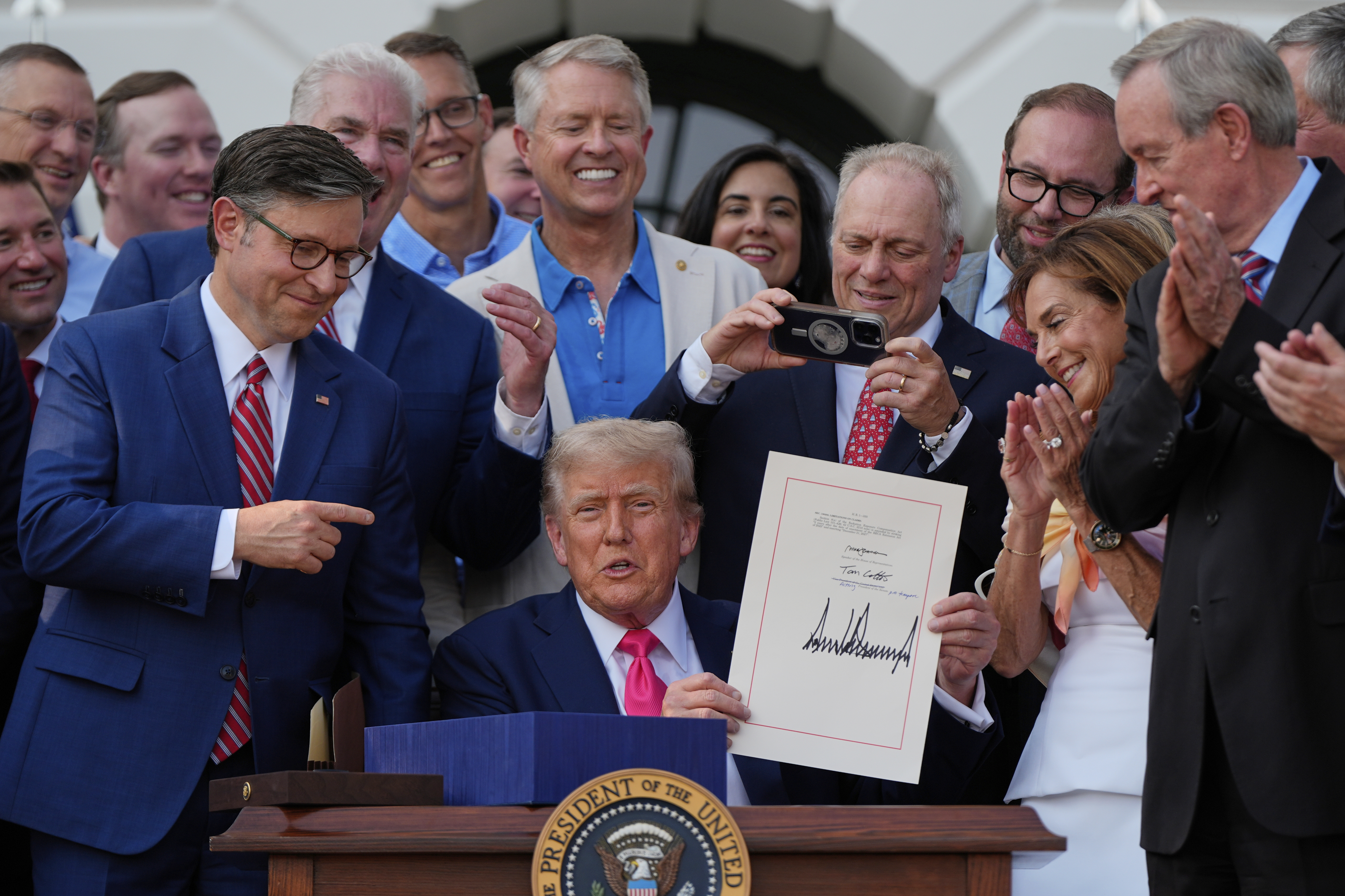 Trump holds up his signature on the One Big Beautiful Bill