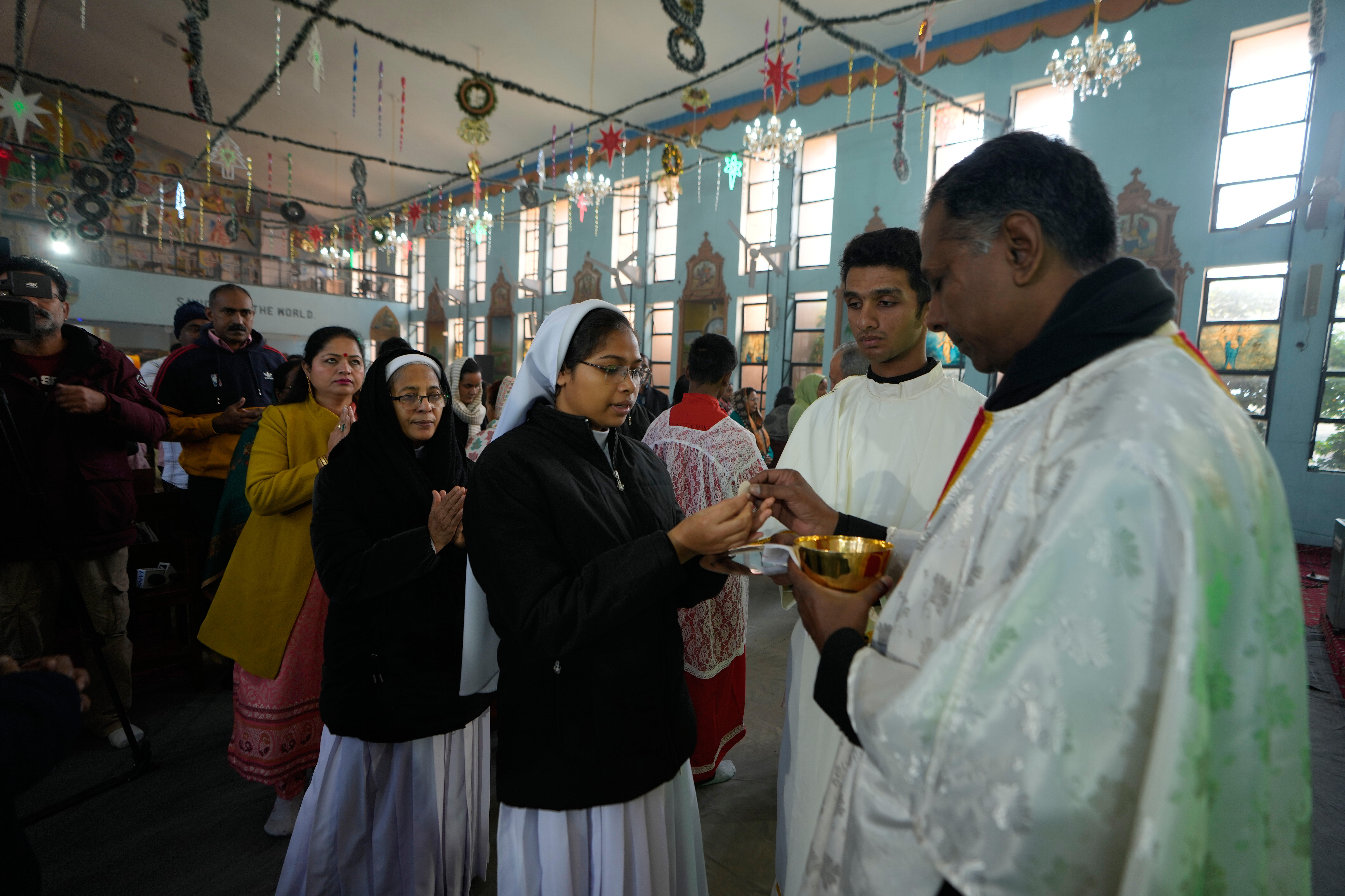 An Indian Christian woman receives holy communion as others wait in a queue during Christmas at St. Mary's Garrison church, in Jammu, India, Thursday, Dec.25, 2025. (AP Photo/Channi Anand)