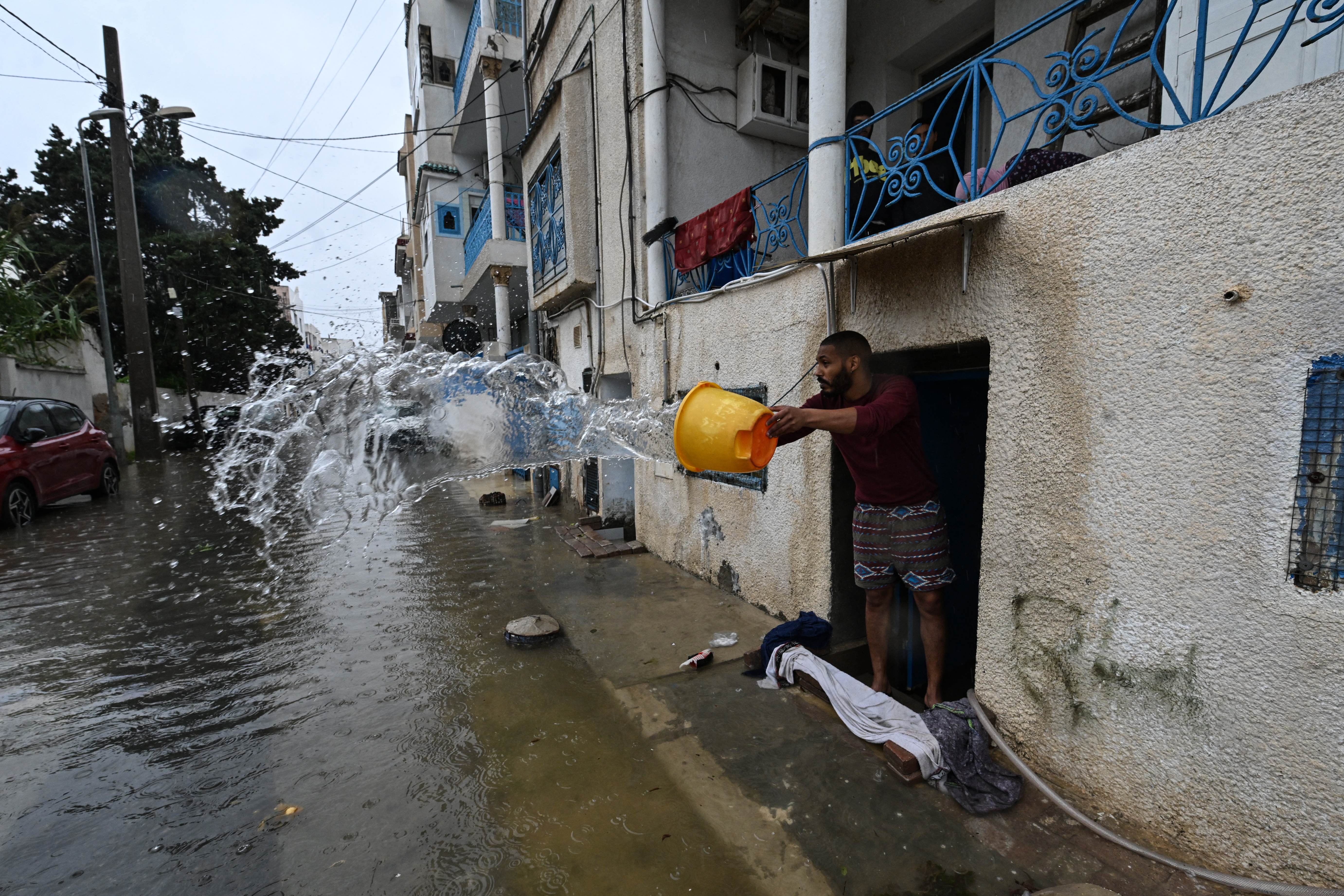 A man uses a bucket to remove flood water from his home, in La Goulette near the capital Tunis, on Januray 20, 2026.