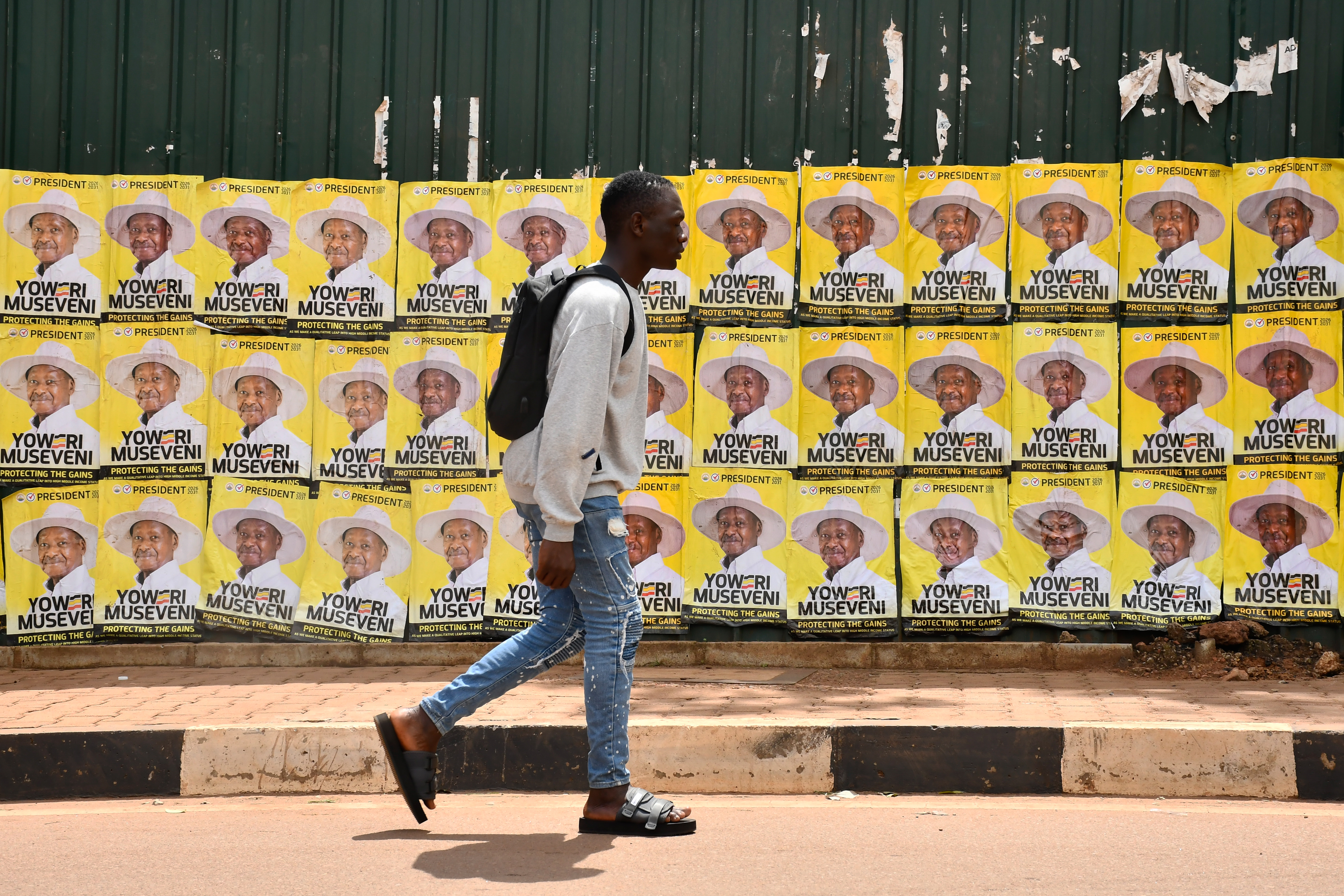 epa12646498 A man walks past posters of incumbent Ugandan President and National Resistance Movement (NRM) presidential candidate Yoweri Museveni in Kampala, Uganda, 13 January 2026. Eight presidential candidates, including Museveni and NUP candidate Bobi Wine, are vying for the presidency in Uganda, scheduled for 15 January. Museveni seeks a seventh term after four decades in power. EPA/ISAAC KASAMANI