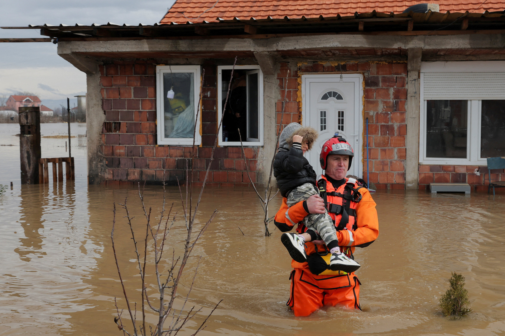 A rescue worker evacuates a child from a flooded house due to heavy rainfall in the village of Kuzmin, Kosovo on Jan. 7, 2026. [Valdrin Xhema/Reuters]