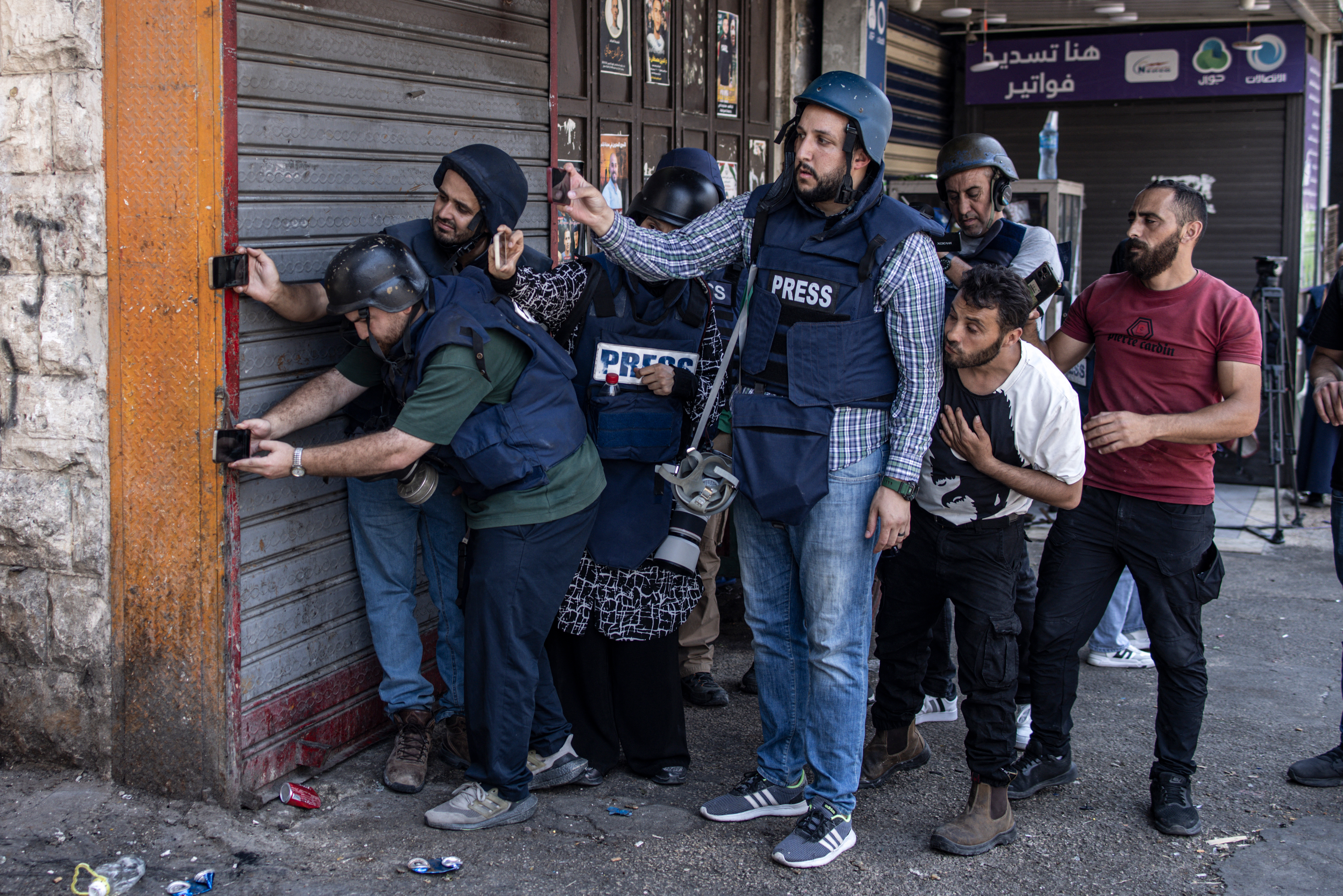 Palestinian journalists take cover after a man was shot dead by Israeli forces during a large-scale military raid in the old town of Nablus city in the occupied West Bank
