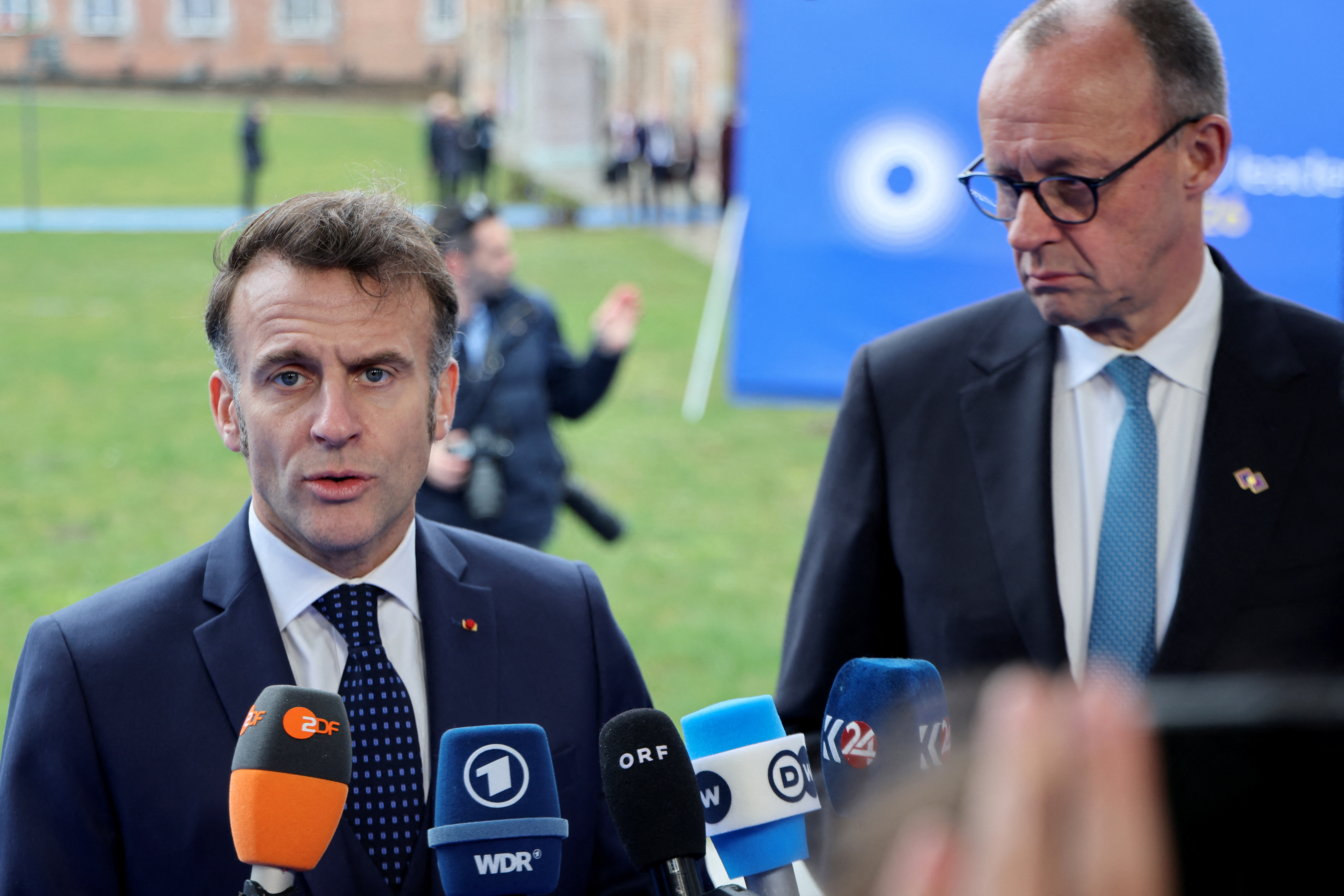 France's President Emmanuel Macron (L) and Germany's Chancellor Friedrich Merz speak to the press upon their arrival in Alden Biesen, Belgium on February 12, 2026.