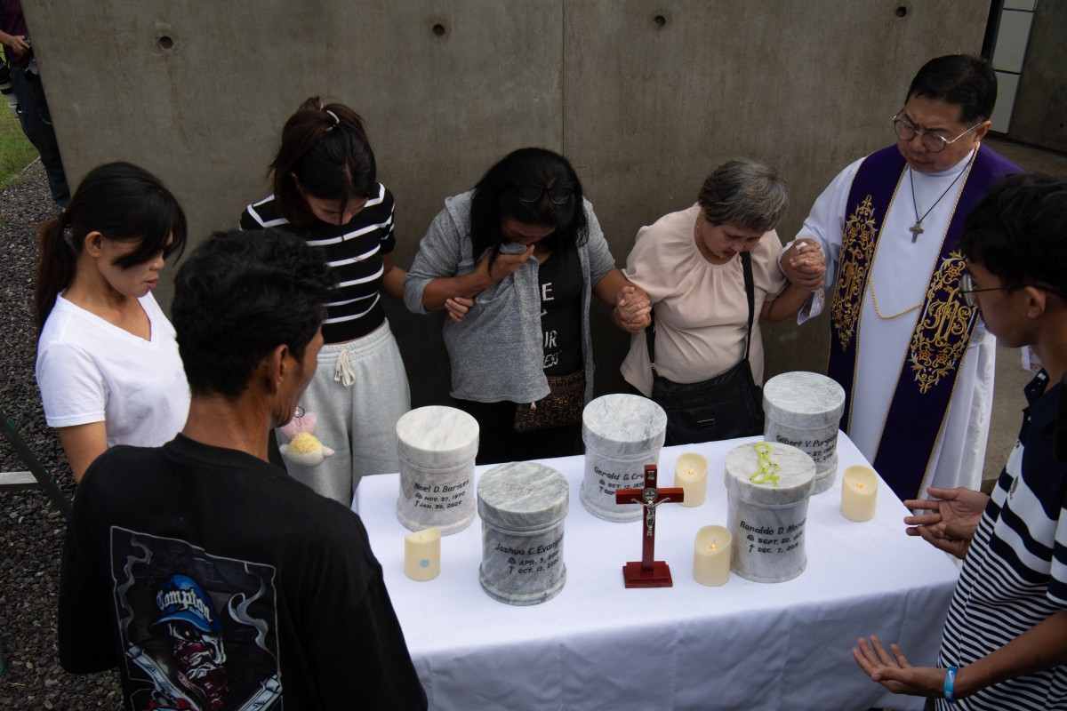 Catholic priest Father Flavie Villanueva (R) joins hands with relatives of extrajudicial killings of former Philippine president Rodrigo Duterte's drug war during the inurnment rites at the "Dambana ng Paghilom" (Shrine of Healing) at a cemetery in Caloocan city, suburban Manila on February 20, 2026.A hearing begins at the International Criminal Court (ICC) on February 23 that will determine whether Duterte will stand trial over at least 76 of those deaths.