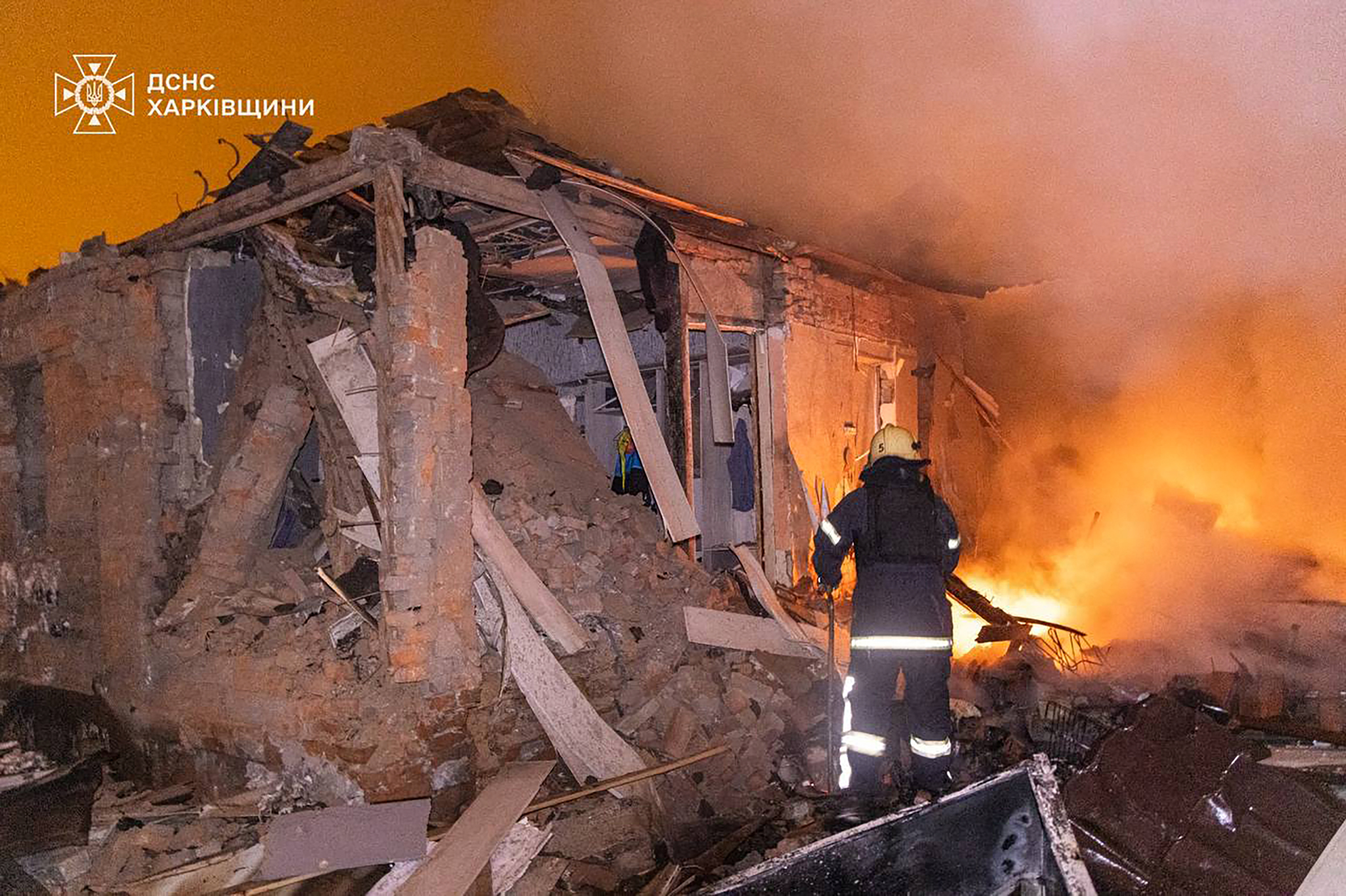 A firefighter extinguishes a fire in a damaged house following a Russian attack in Kharkiv